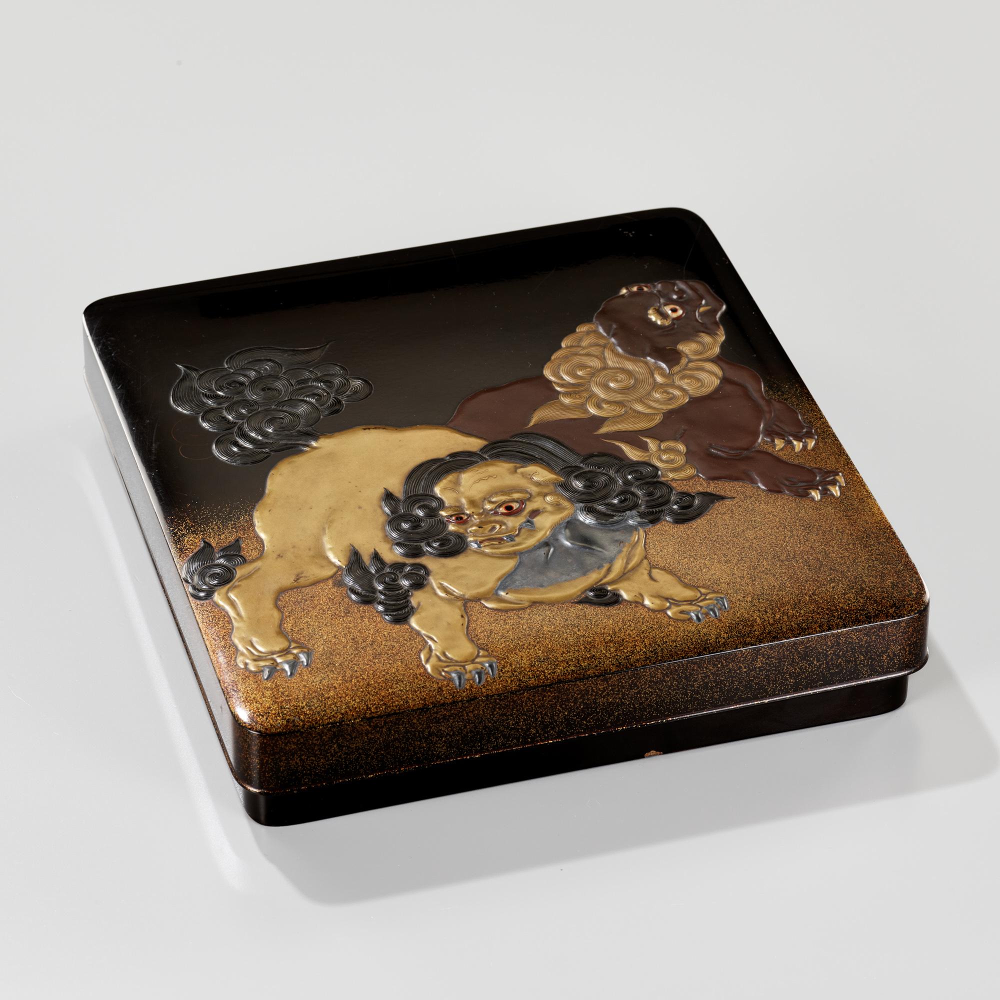 A captivating lacquer suzuri’bako (writing box) of rounded rectangular form depicting a pair of shishi (temple lions) and the lucky god Hotei 布袋 on a rôiro’urushi (black lacquer) ground. Hotei is the god of contentment and happiness, guardian of