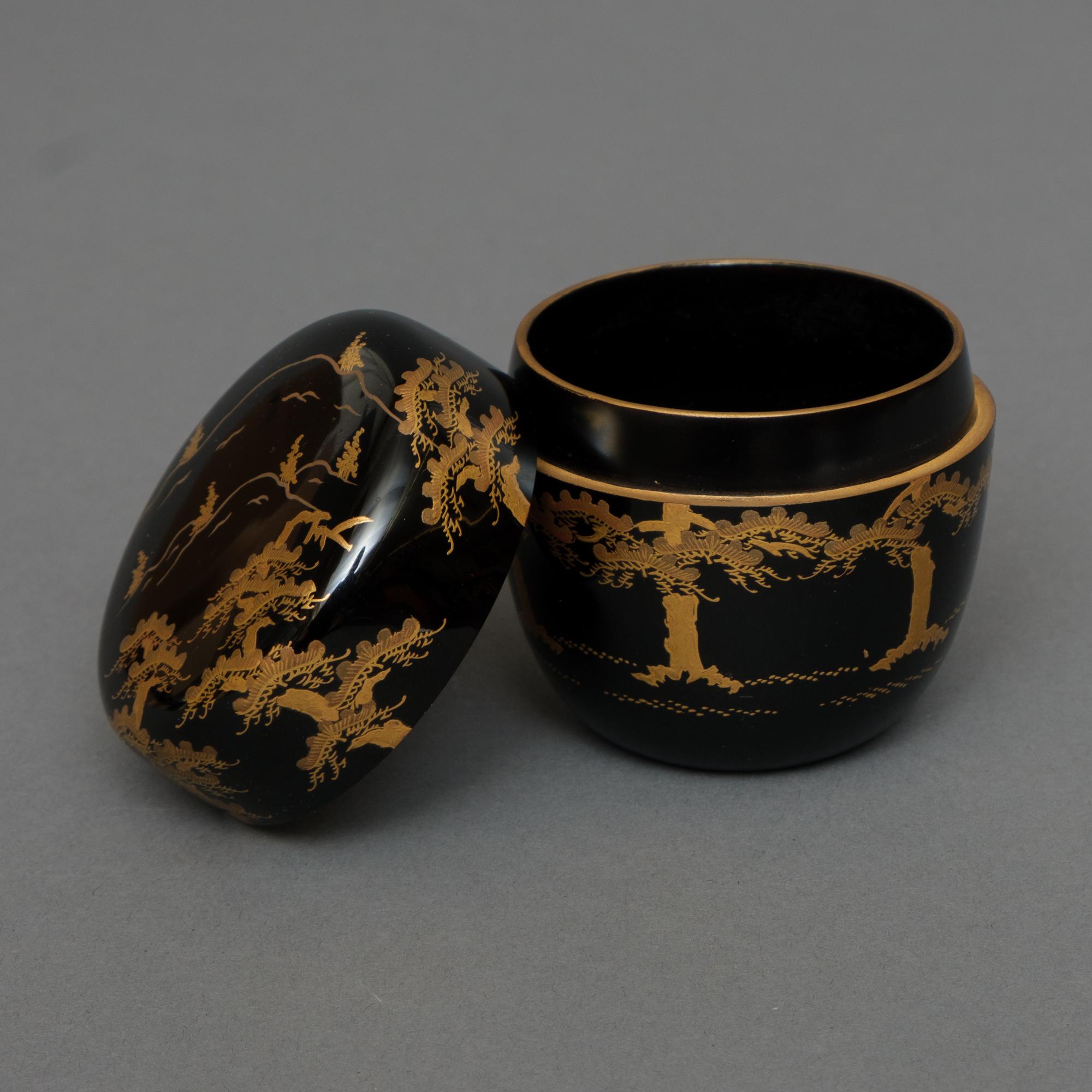 Pretty lacquer tea caddy (natsume) with refined hiramaki-e (low-relief lacquer design) showcasing a pine tree forest (matsu) at the base of a mountain.
Executed in shades of gold lacquer on a glossy black lacquer substrate ground. The interior done