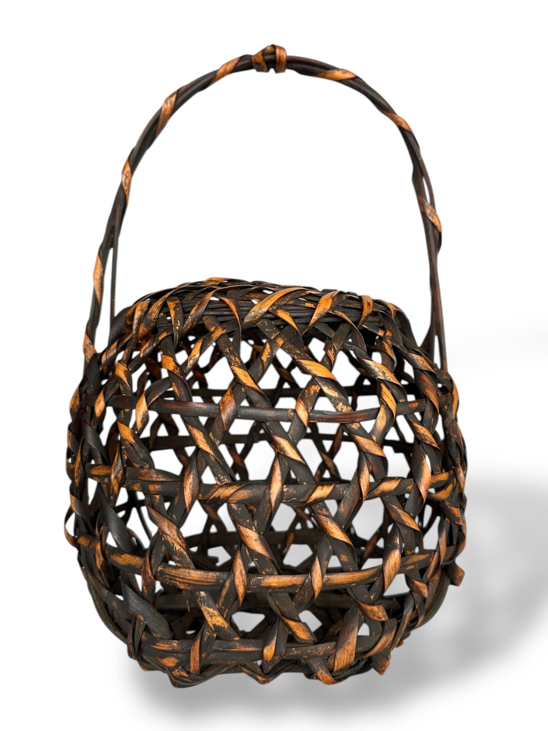 Japanese Lacquered Bamboo Basket with Twisted Handle
Japan, 20th Century
Dimensions: H 36 cm (including handle), W 23 cm × D 20 cm

This sculptural Japanese flower basket (hanakago) is finely woven from dark-stained bamboo with a dynamic