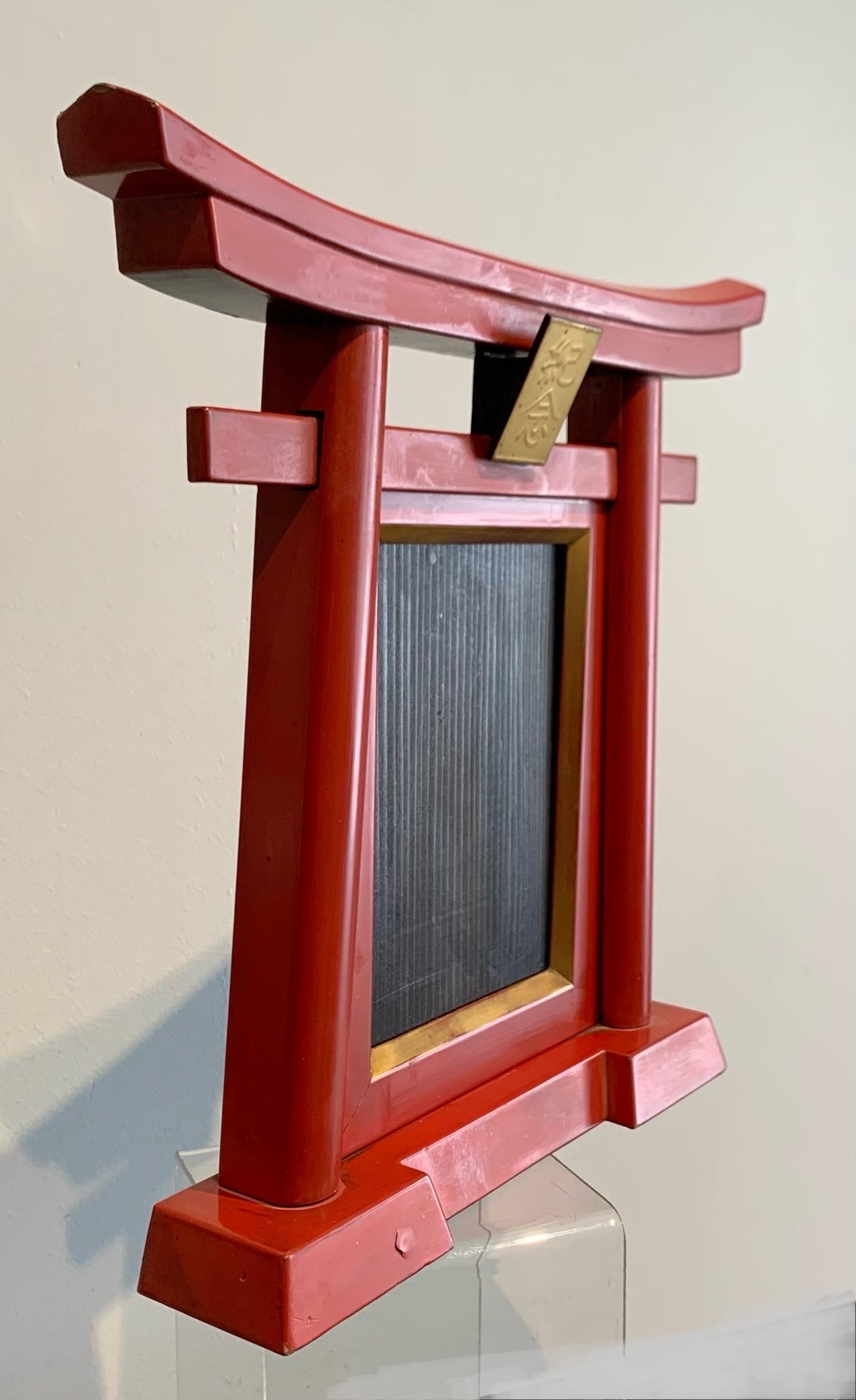 Red and black lacquered wooden frame, depicting a Japanese temple door. 
Torii gate with golden pediment.
Ideal format for photo (13.2 x 9.2 cm)
soft blackened bamboo bindings on the back