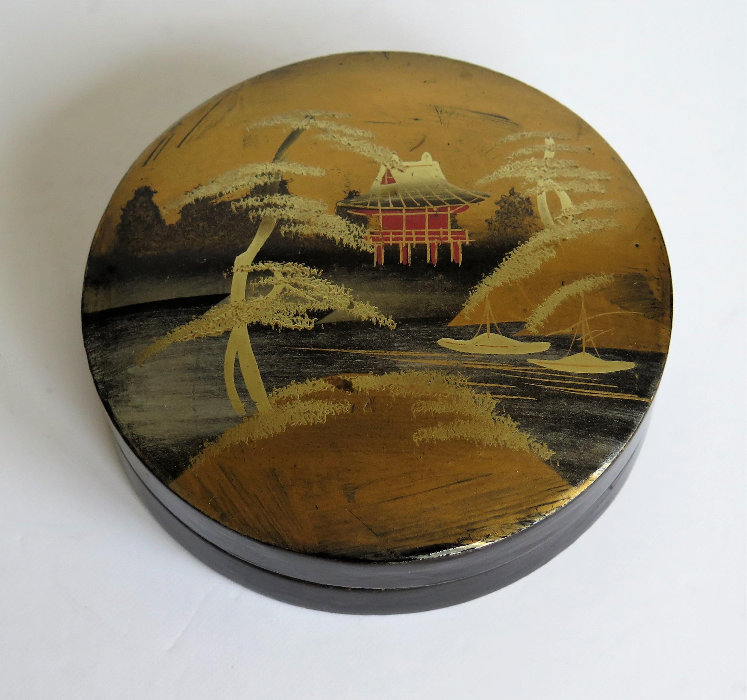 This is a beautiful papier mâché, circular lacquered lidded box, which we attribute to being made in Japan, very early in the 20th century, late Meiji period, circa 1900.

This is a very decorative box with a delicately hand painted waterside