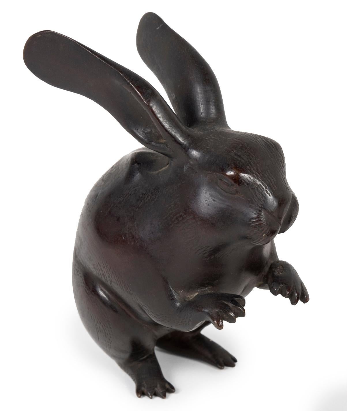 Round hare in bronze with a dark brown patina, standing on two legs. 
In Japanese, the hare and the rabbit are referred to by a single word: usagi. The animal is one of the twelve animals of the zodiac in Sino-Japanese astrology. It also plays a