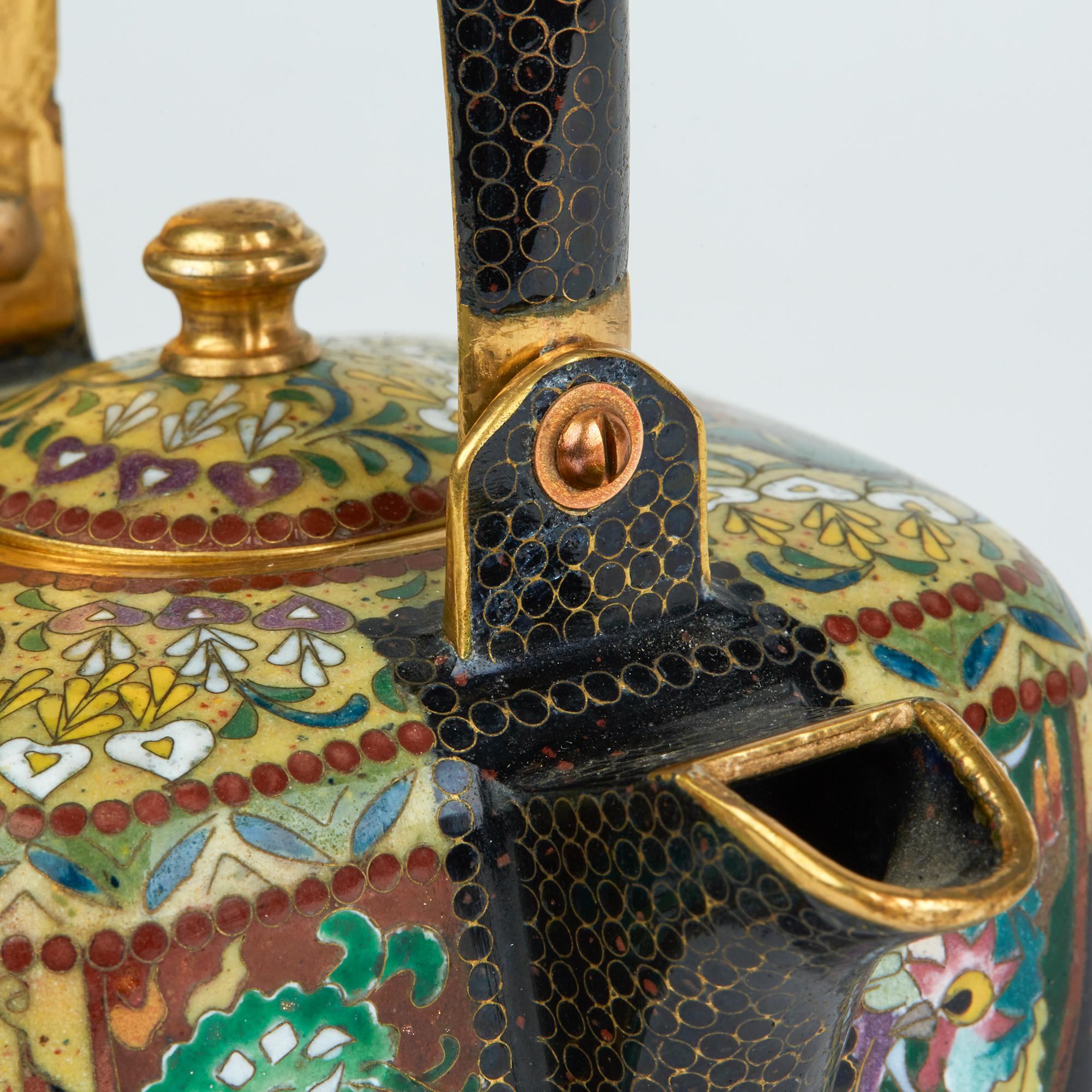 An exceptional antique Japanese cloisonné lidded kettle shaped teapot with gilded metal finish believed to date from the early to mid-20th century. The teapot of square shape stands raised on four small ball shaped feet and is richly and finely