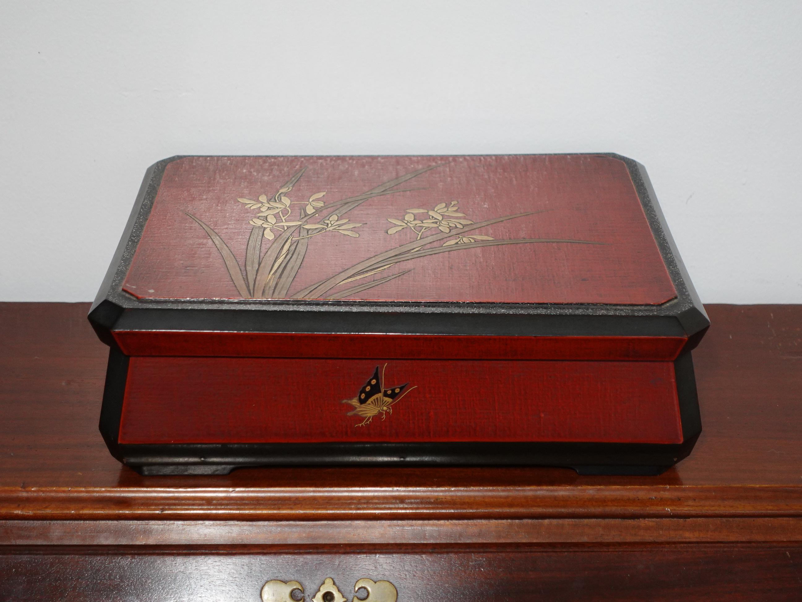 Japon, fin de la période Meiji Une grande boîte d'organisation en laque rouge, décorée d'iris et de papillons en or et noir.