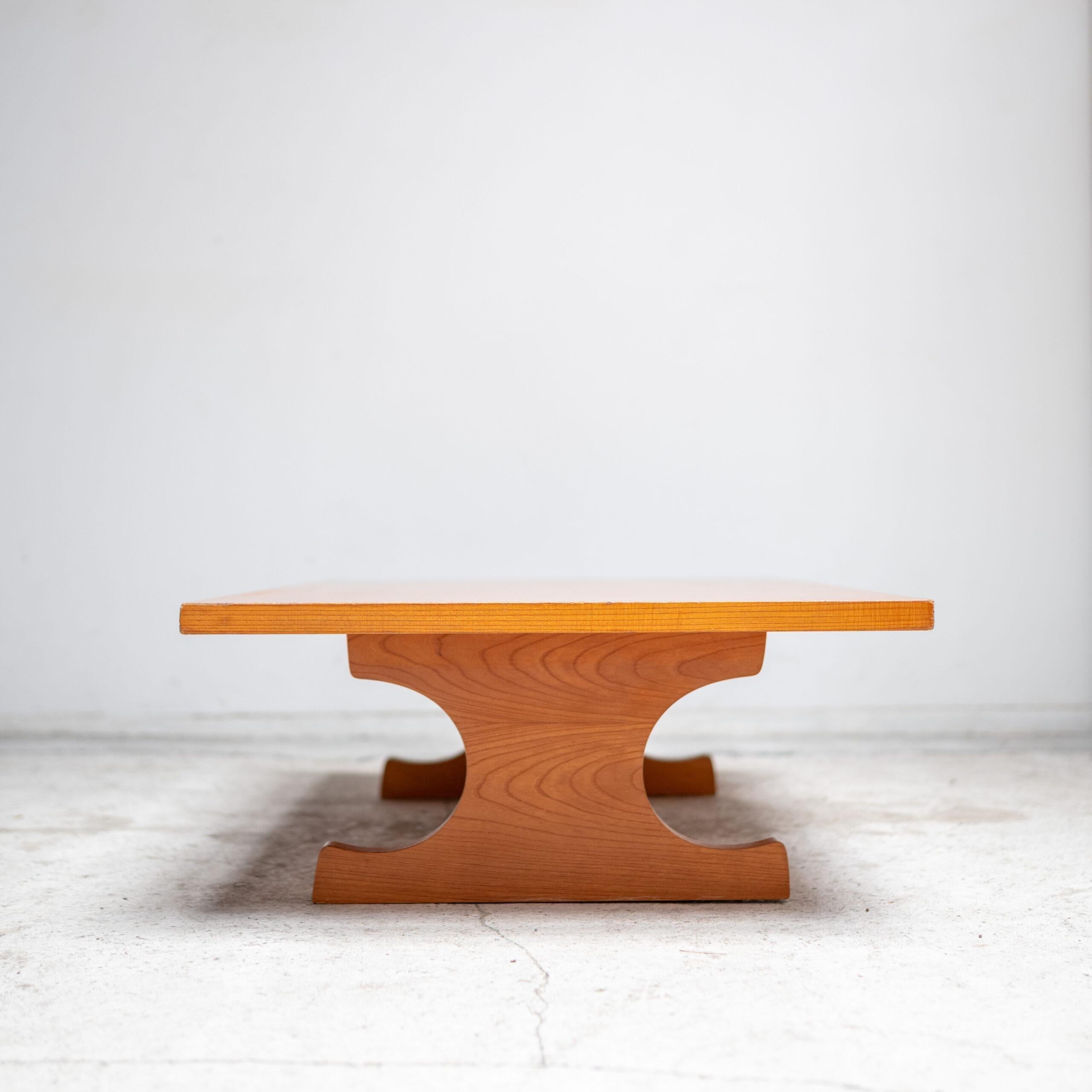 Una escultural mesa baja de madera maciza, que muestra la elegante simetría y la refinada artesanía típicas del diseño moderno japonés.