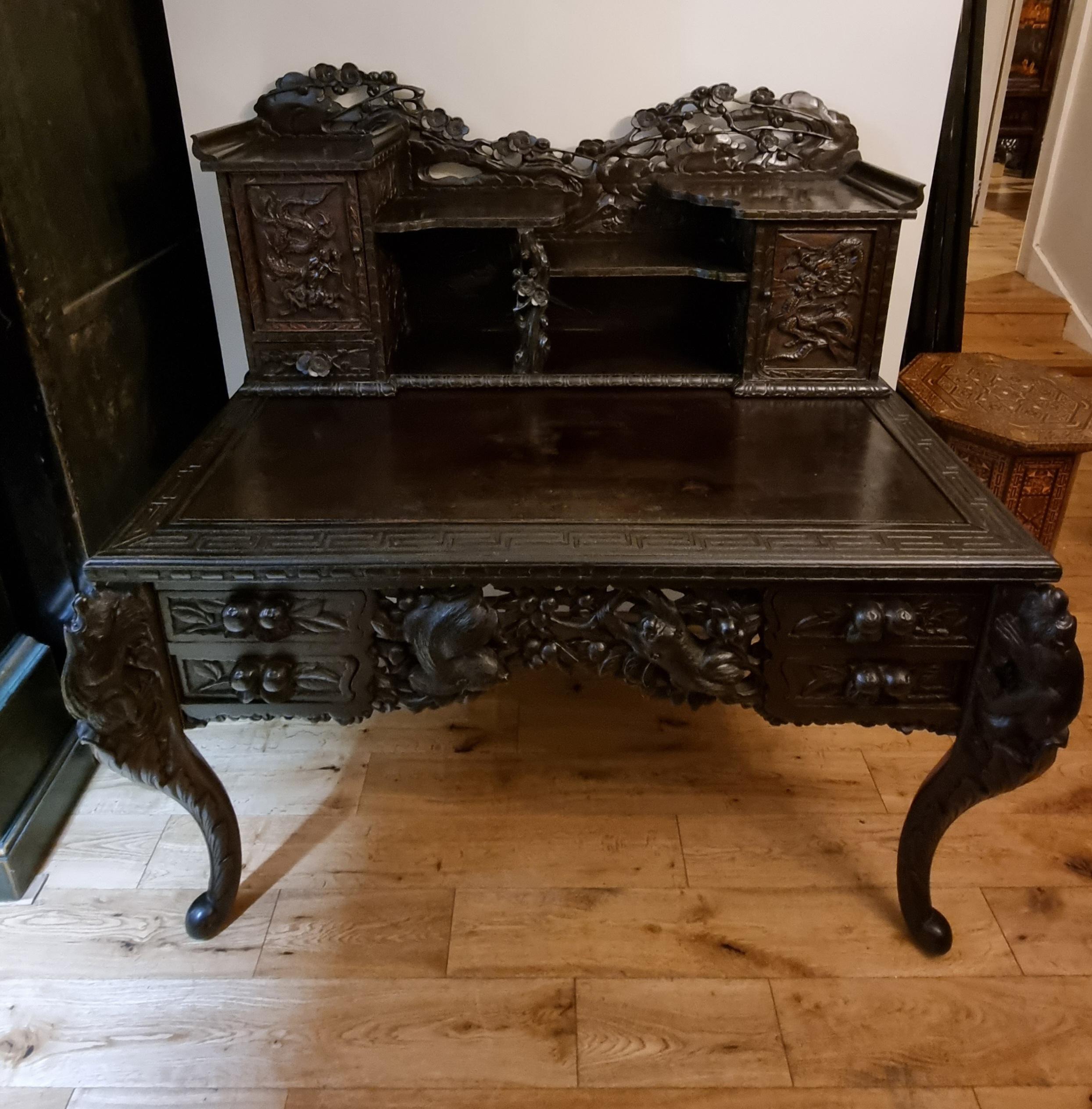 Scrittoio giapponese del periodo Meiji risalente alla fine del XIX secolo, squisitamente intagliato a mano, in legno duro laccato. Un'incantevole serie di intricati intagli, tra cui raffigurazioni ad alto rilievo di draghi, motivi floreali e