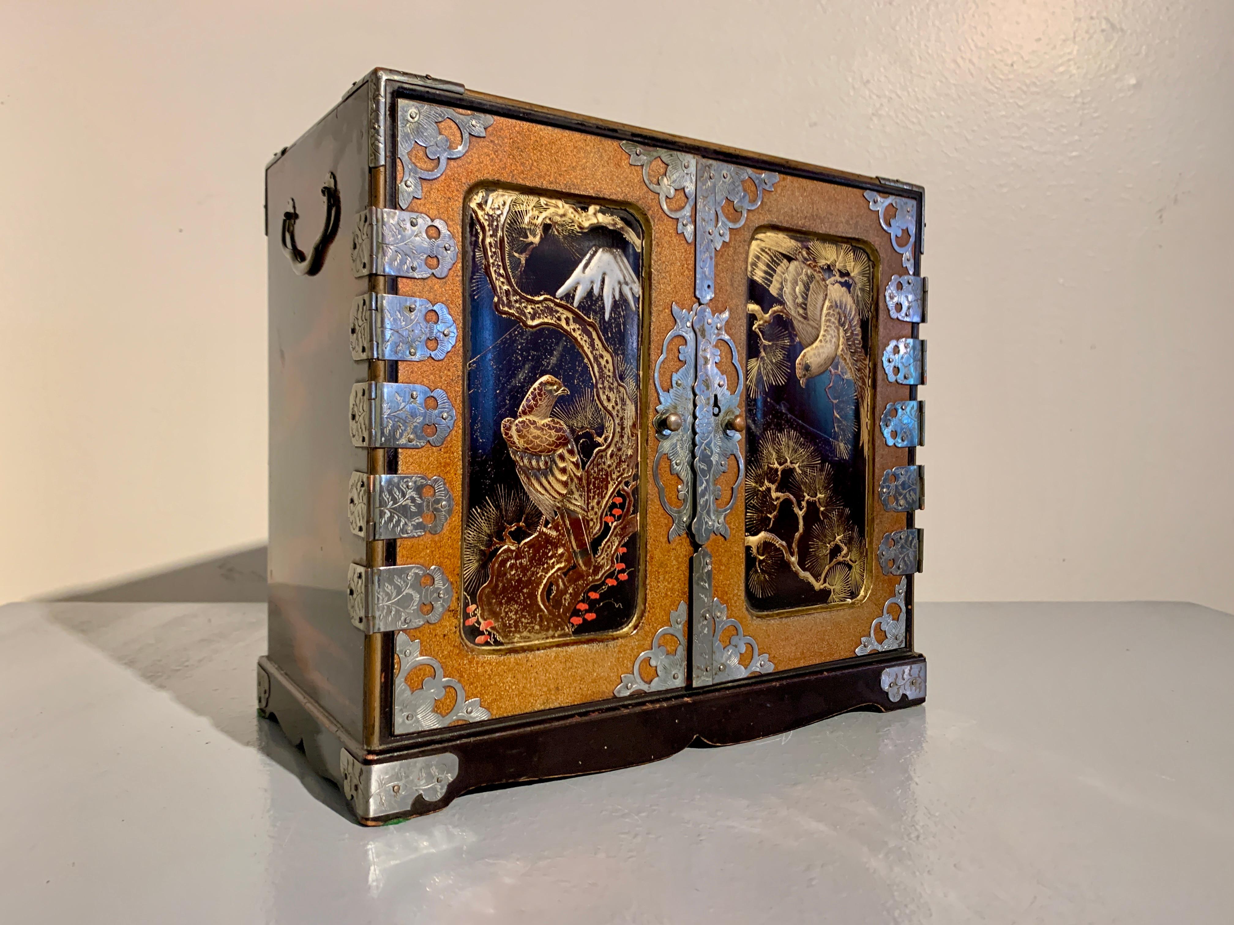 A delightful and powerful small Japanese lacquer table cabinet, suitable for use as a jewelry box or collector's chest, with a design of hawks, pine, and Mt. Fuji, Meiji Period, circa 1900, Japan.

The small chest or cabinet of traditional form, set