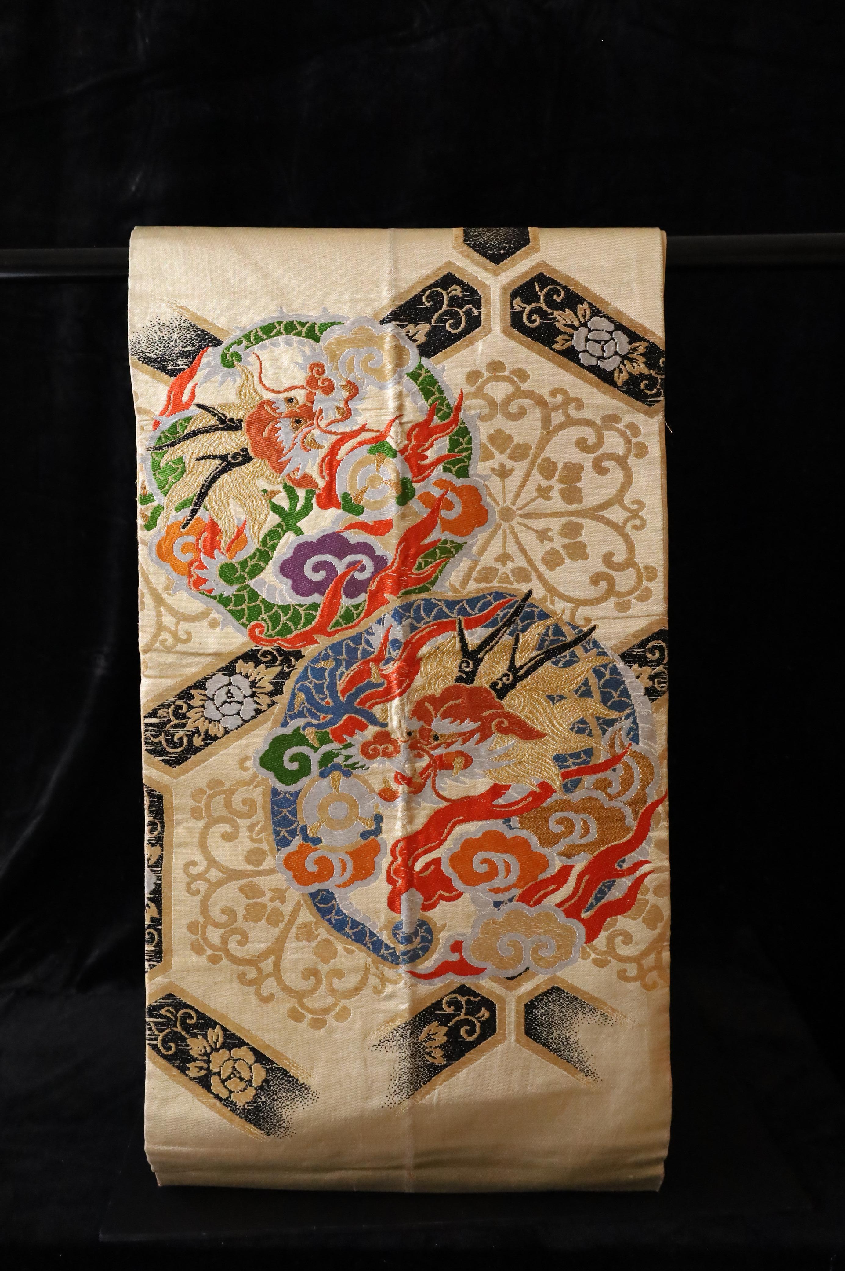 A magnificent example of Japanese textile artistry, this vintage maru obi dates from the Taisho to early Showa period (circa 1920–1950). Woven in luxurious silk, it features a richly detailed brocade design with mythological dragons encircled by