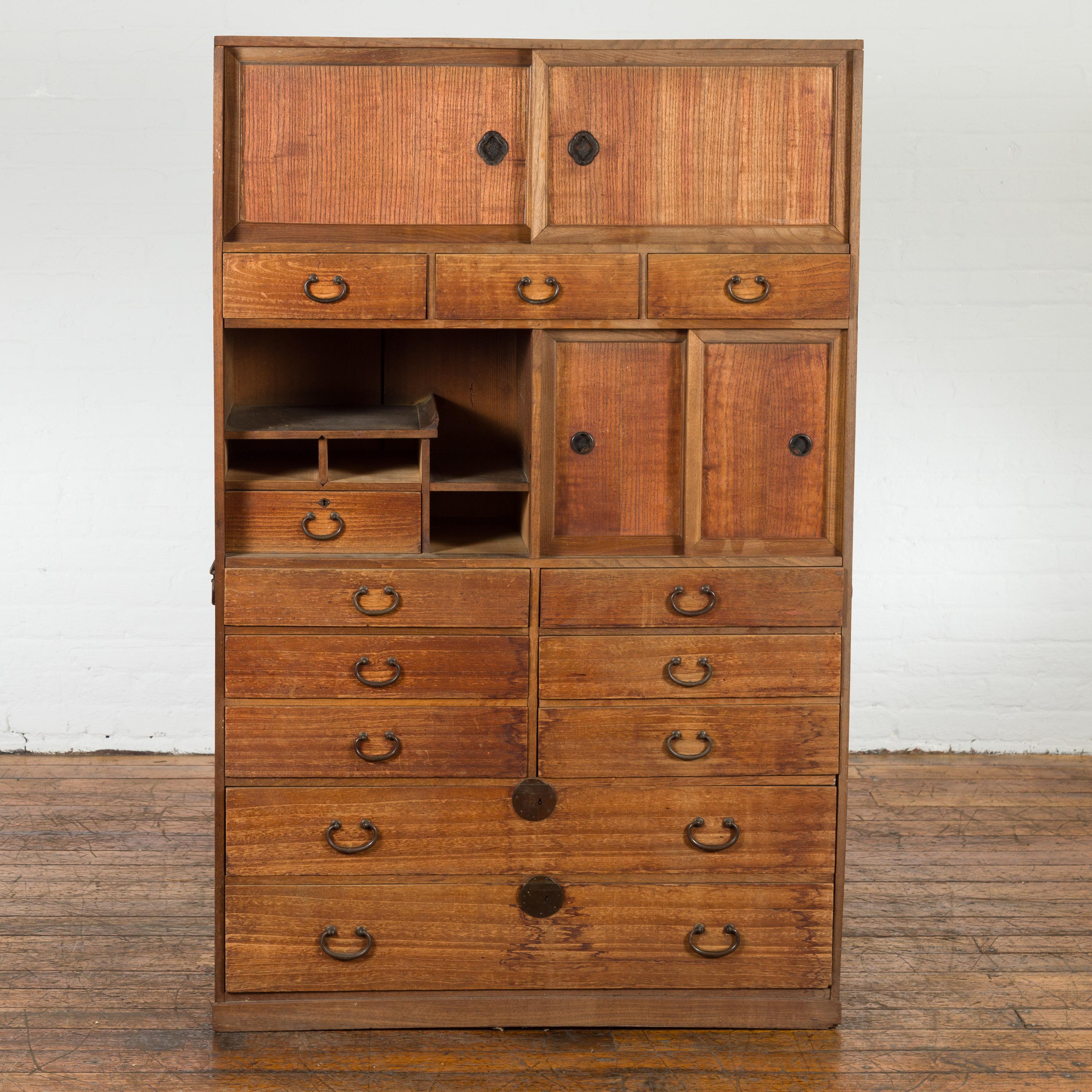 A Japanese Meiji period kiri wood cha tansu tea cabinet from the 19th century, with sliding doors, multiple drawers and brass hardware. Created in Japan during the Meiji period in the 19th century, this tansu chest is made of kiri wood (also known