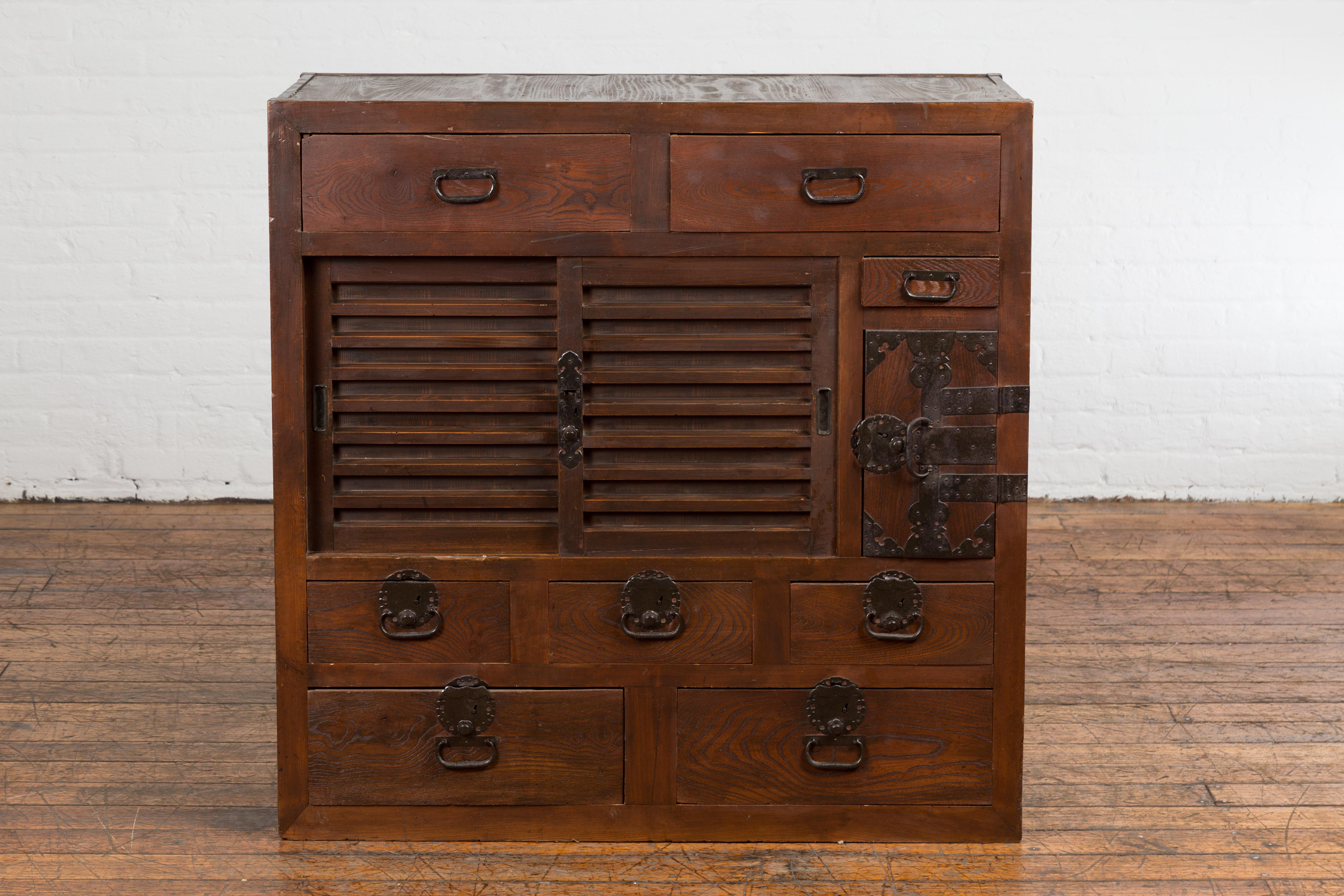 A Japanese Meiji period choba dansu merchant's chest from the 19th century with sliding doors, eight drawers, side door opening to two additional drawers and iron hardware. This 19th-century Japanese choba dansu merchant's chest, a quintessential