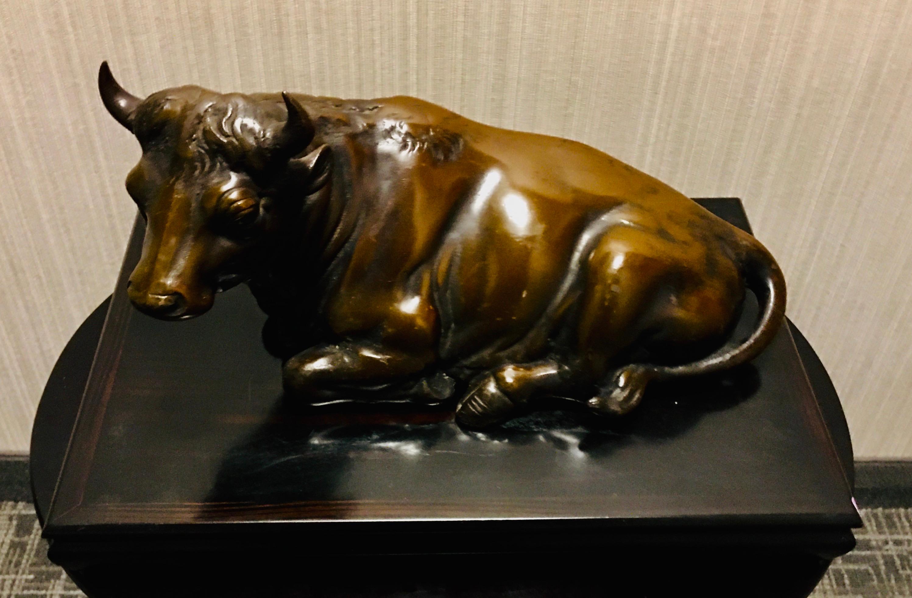 Japanese Meiji period bronze cast resting cow sculpture, placed on a fine lacquered presentation stand. The piece dates from the Meiji period, circa 1880.
In great antique condition with minor aging.

Measures: 17’” L x 8” H x 5 1/2 W
Lacquered