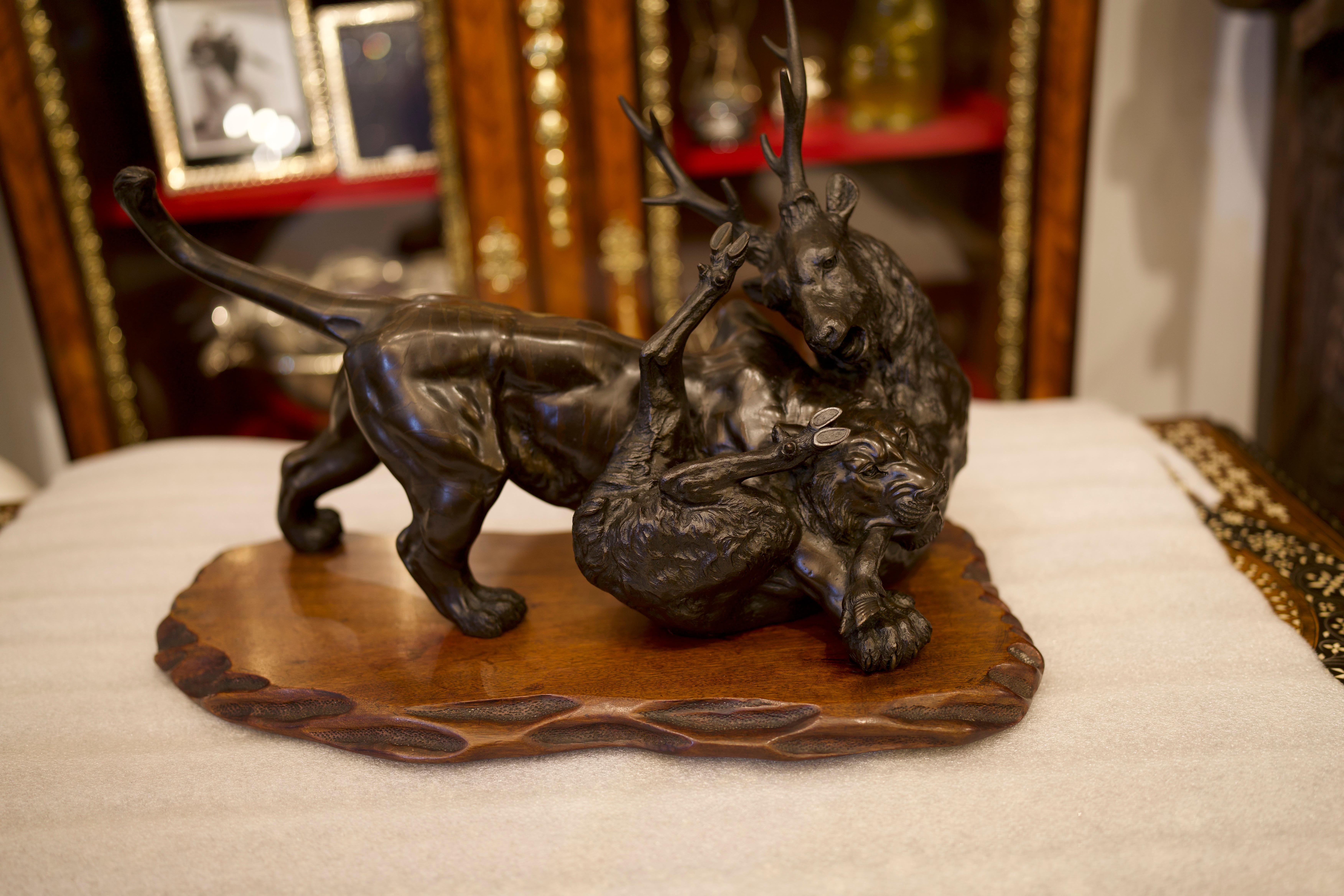 A stunning Japanese Meiji Bronze on Hardwood Base Tiger/Antelope, 19th Century. The tiger presents strength, vitality, and growth. The artist has captured the virtues beautifully in this piece, resembling a strong and powerful visual.