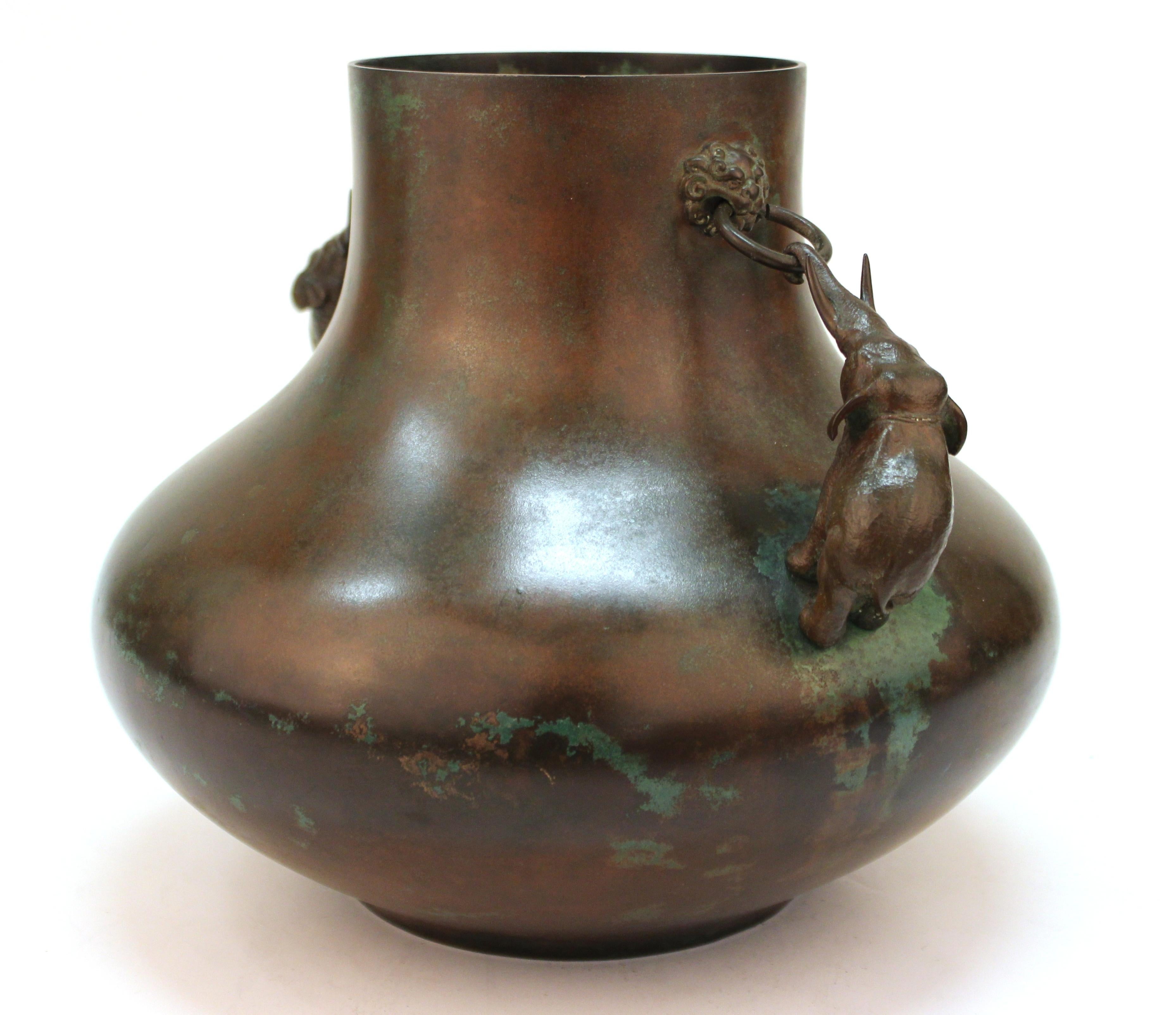 Japanese Meiji period bronze vase with two sculpted elephants pulling on the ring handles with their trunks. The piece has a desirable natural green patina and a makers stamp on the bottom. In great vintage condition.