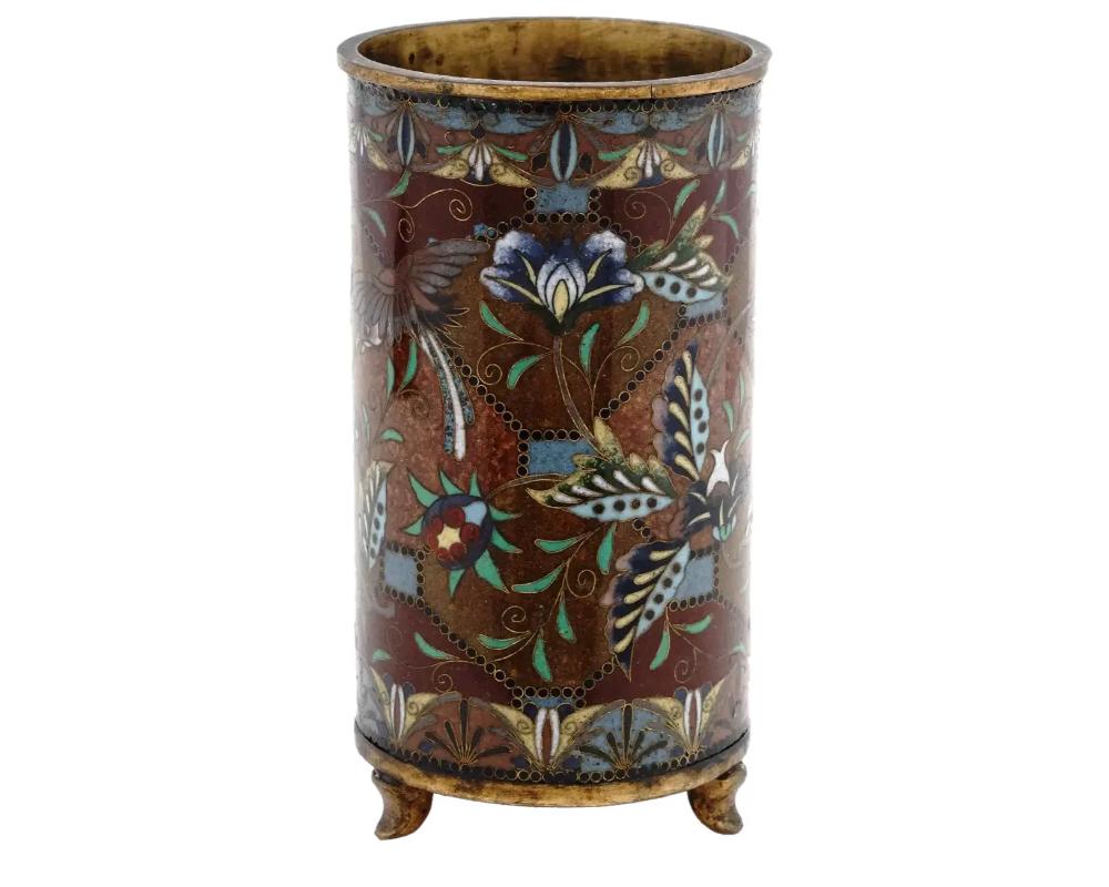 An antique Japanese Meiji Era enamel over brass brush pot. The cylindrical form pot is enameled with polychrome images of blossoming flowers and birds, and a geometrical ornament made in the Cloisonne technique. The neck and the base of the pot are