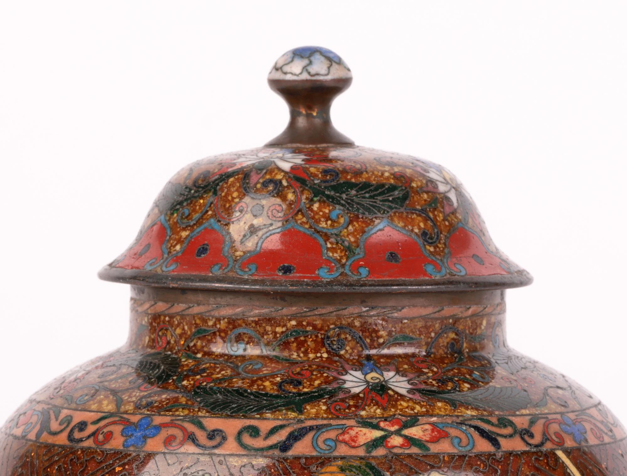 A very fine Japanese Meiji cloisonne lidded jar decorated with butterflies amidst bamboo and flowering shrubs dating from the latter 19th Century. The jar of rounded bulbous shape stands on a narrow round foot with a raised narrow neck and hat