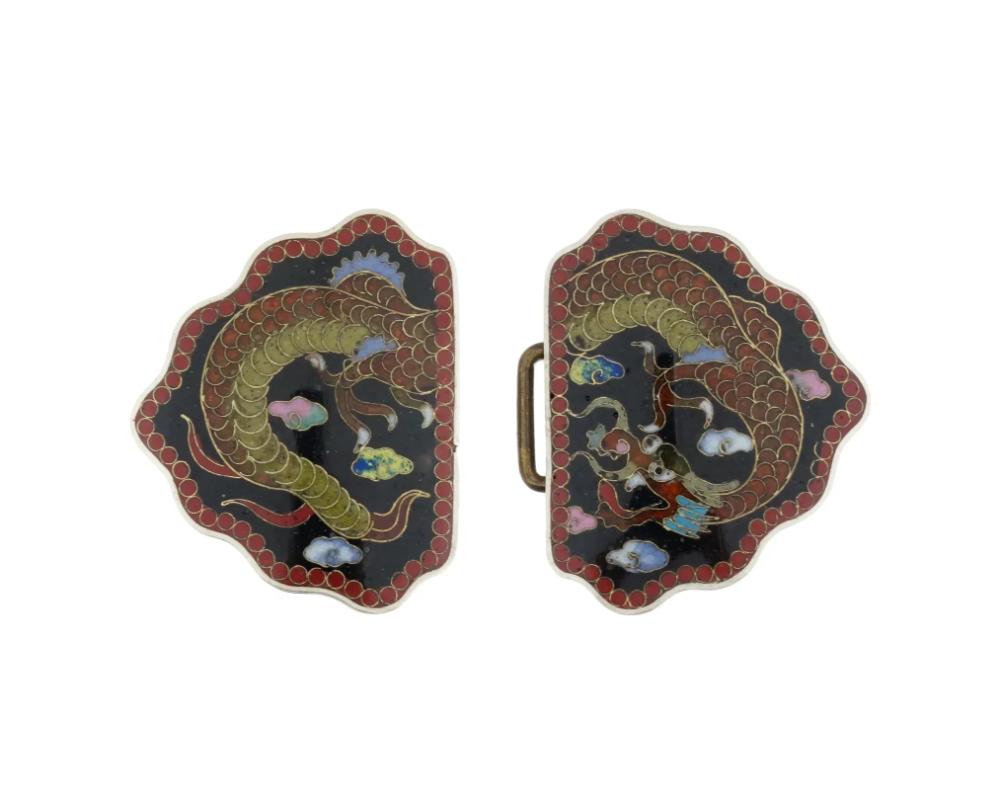 An antique Japanese, late Meiji era, enamel over copper belt buckle. The ware consists of two parts with a clasp. The belt buckle is covered with a polychrome design representing a dragon in clouds surrounded by a geometrical ornament on the borders
