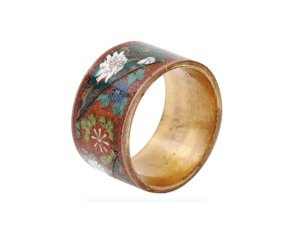 An antique Japanese Meiji Era copper and enamel napkin ring. circa: late 19th century to early 20th century. The ware is enameled with polychrome floral, and foliage patterns made in the Cloisonne technique. Unmarked. The borders are enameled with a