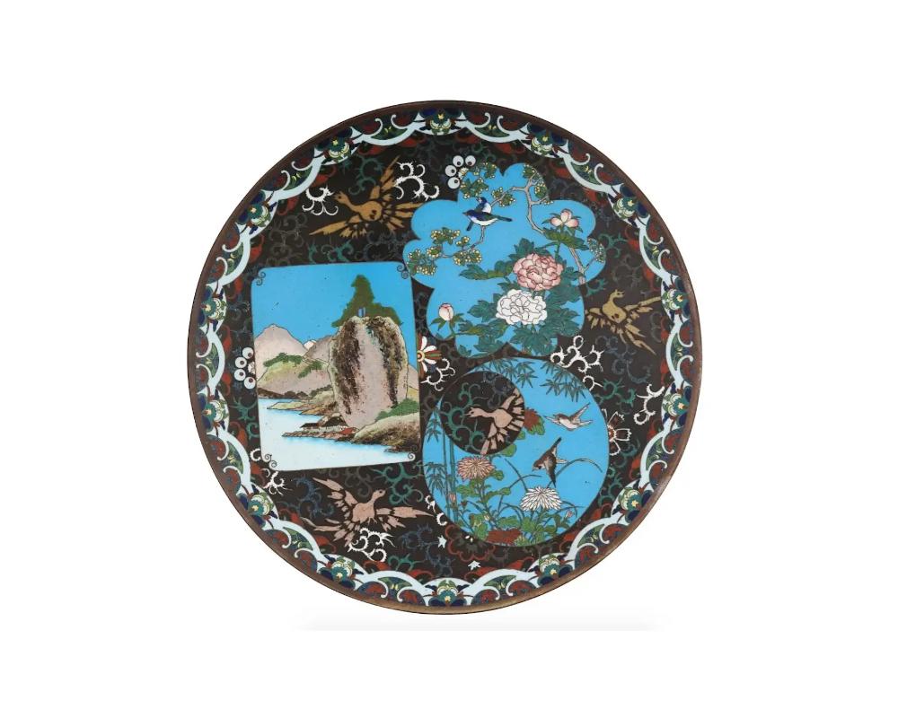 An antique Japanese, Meiji era, enamel over brass charger or plate. The plate is adorned with polychrome medallions depicting birds in chrysanthemum flowers, and a river mountain landscape view surrounded by Phoenix bird, floral, foliage, and