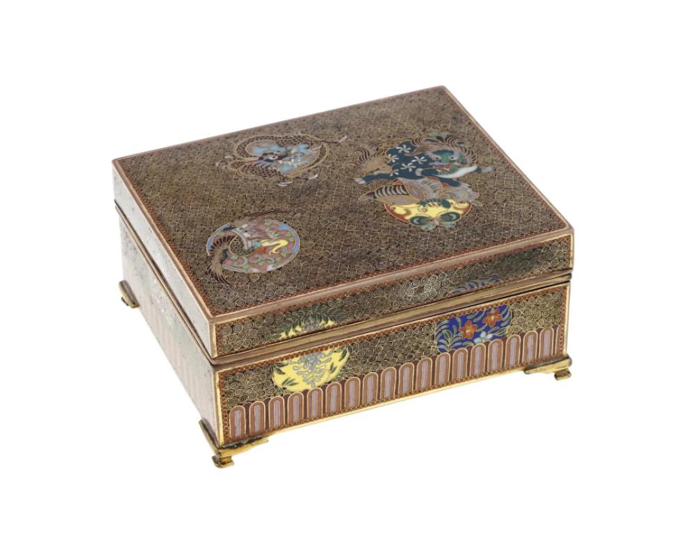 An antique Japanese copper footed rectangular double-bottom box with hinged lid. Late Meiji period, The piece is decorated with cloisonne enamel depictions of dragons, phoenix bird, flowers against the swirl motif background. Collectible Oriental