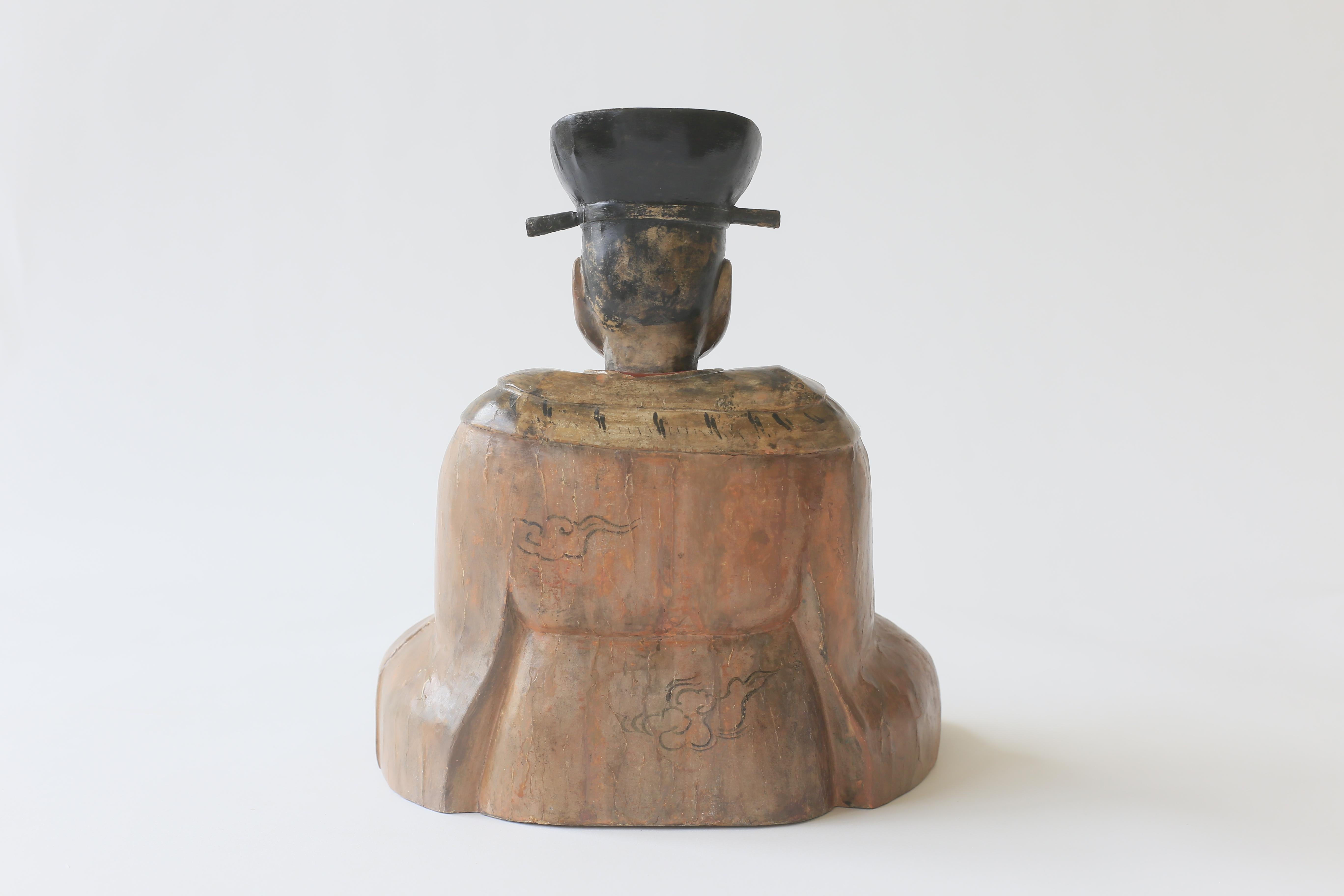 Eine charmante japanische Holzfigur aus der Edo-Periode (1615-1868), sitzend.  Diese Figur ist wahrscheinlich buddhistisch und saß außerhalb eines Tempels.  Die ruhige, sitzende Figur trägt ein Gewand und einen Hut und hält eine Schriftrolle in der