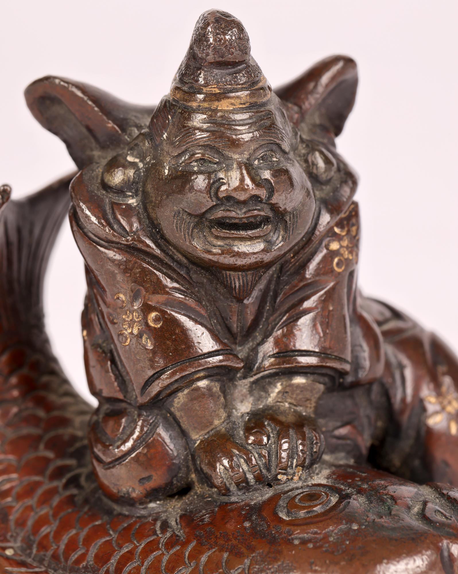 A delightful antique Japanese Meiji Bronze portrayal of a fisherman dating from the 19th century. The fisherman is portrayed with a very large fish and sitting on it to hold it down. The figure is well detailed with gilt patterning and with