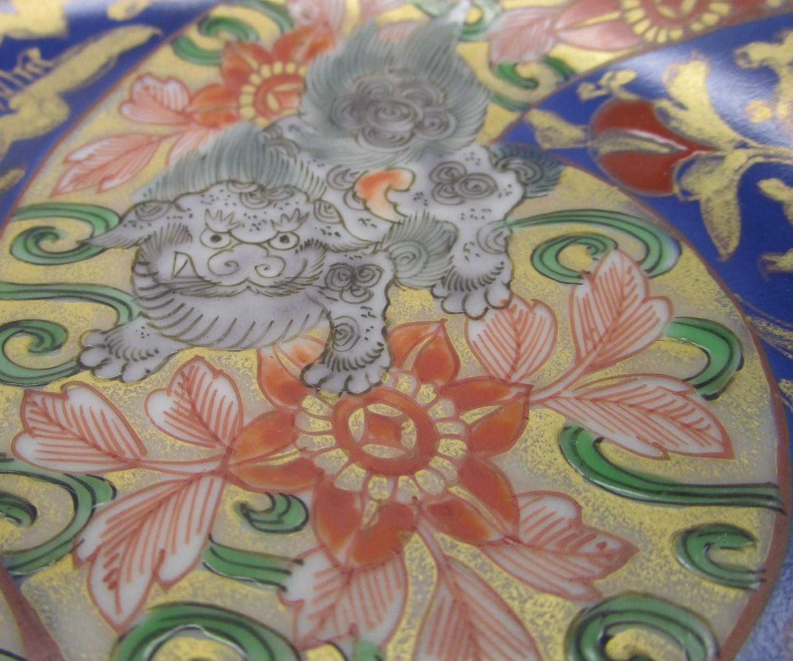 Exquis chargeur japonais de la fin du XIXe siècle, période Imari Meiji (vers 1880), signé en porcelaine rouge fer, bleu cobalt et vert. Il présente trois panneaux à motifs floraux sur un fond doré spectaculaire avec des lions shishi qui se
