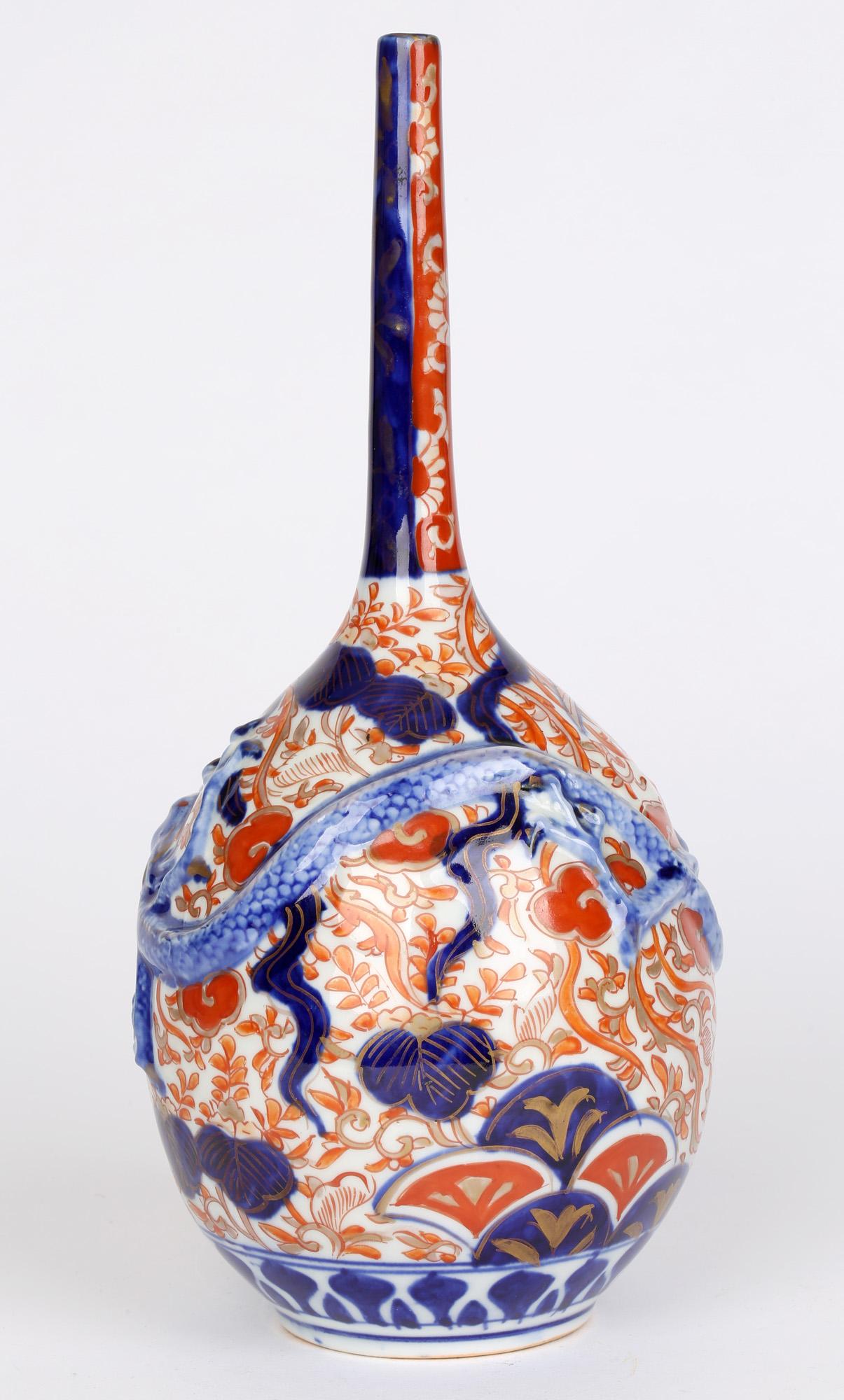 Japanese late Meiji Imari bottle shaped porcelain vase applied with a scrolling dragon dating from between 1868 and 1912. The vase stands on a rounded narrow foot with a rounded egg-shaped body and a very slender tall neck. The body of the vase is