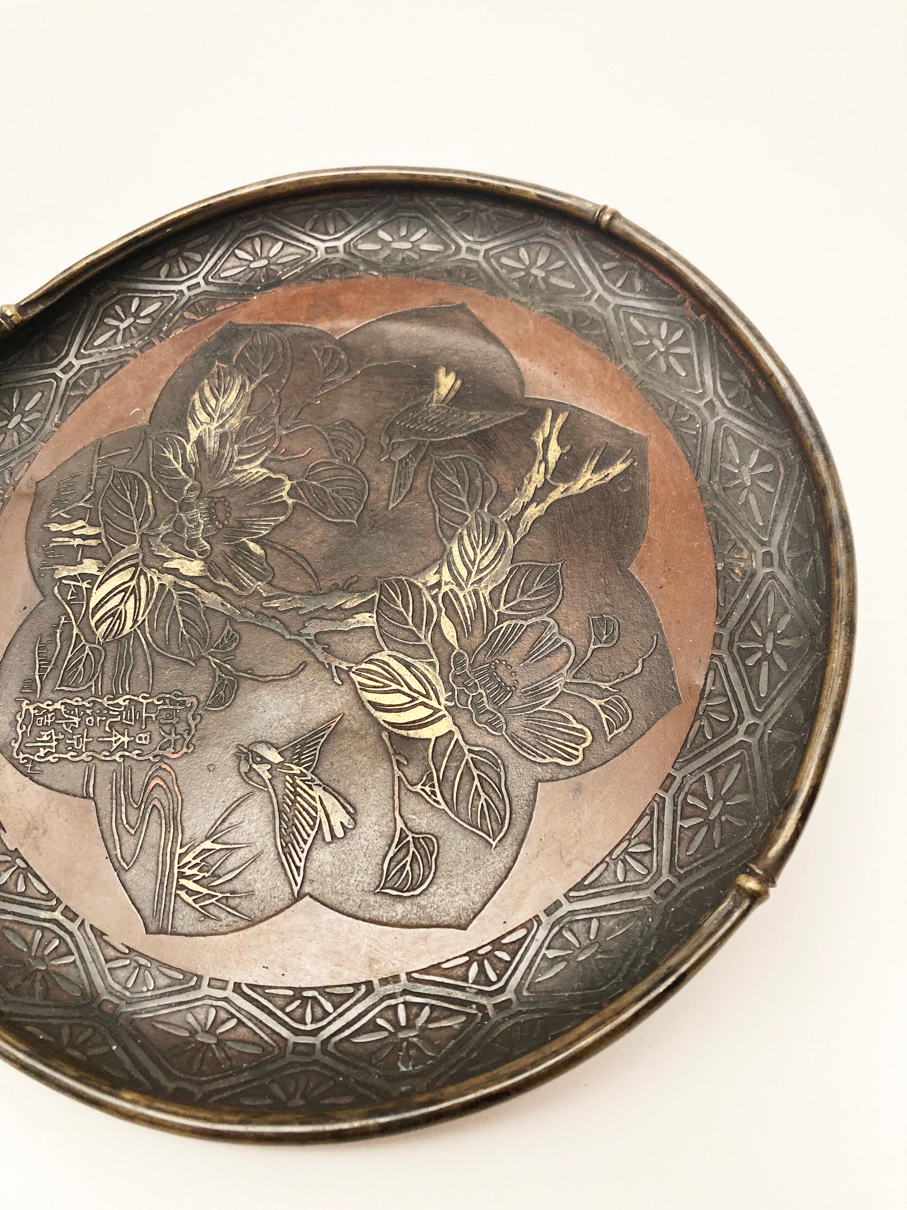 Dieses atemberaubende Werk japanischer Metallarbeit ist brillant in Detail und Handwerkskunst. Die aus Kupfer, Bronze und vielleicht auch anderen Metallen gefertigten Bilder in der Mitte des Tellers sind bemerkenswert. Die Kreation, die