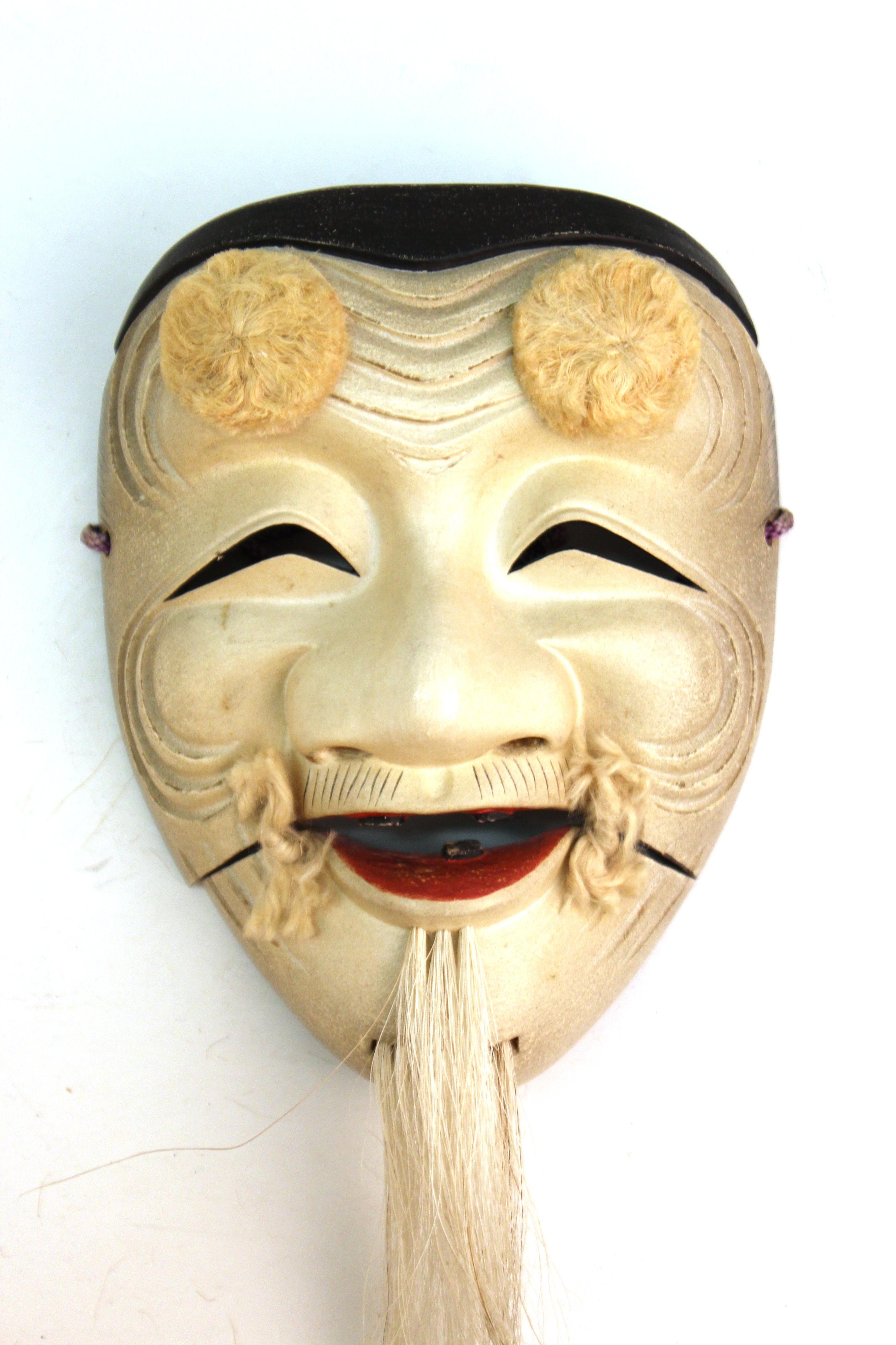 Japanese Meiji period lacquered carved paloma wood Noh mask depicting Okina, the happy old man of wisdom and joy who is a distinguished character in many Noh dramas. This mask was carved circa 1890-1900 by Ko-Ikiu, from a long line of Noh mask