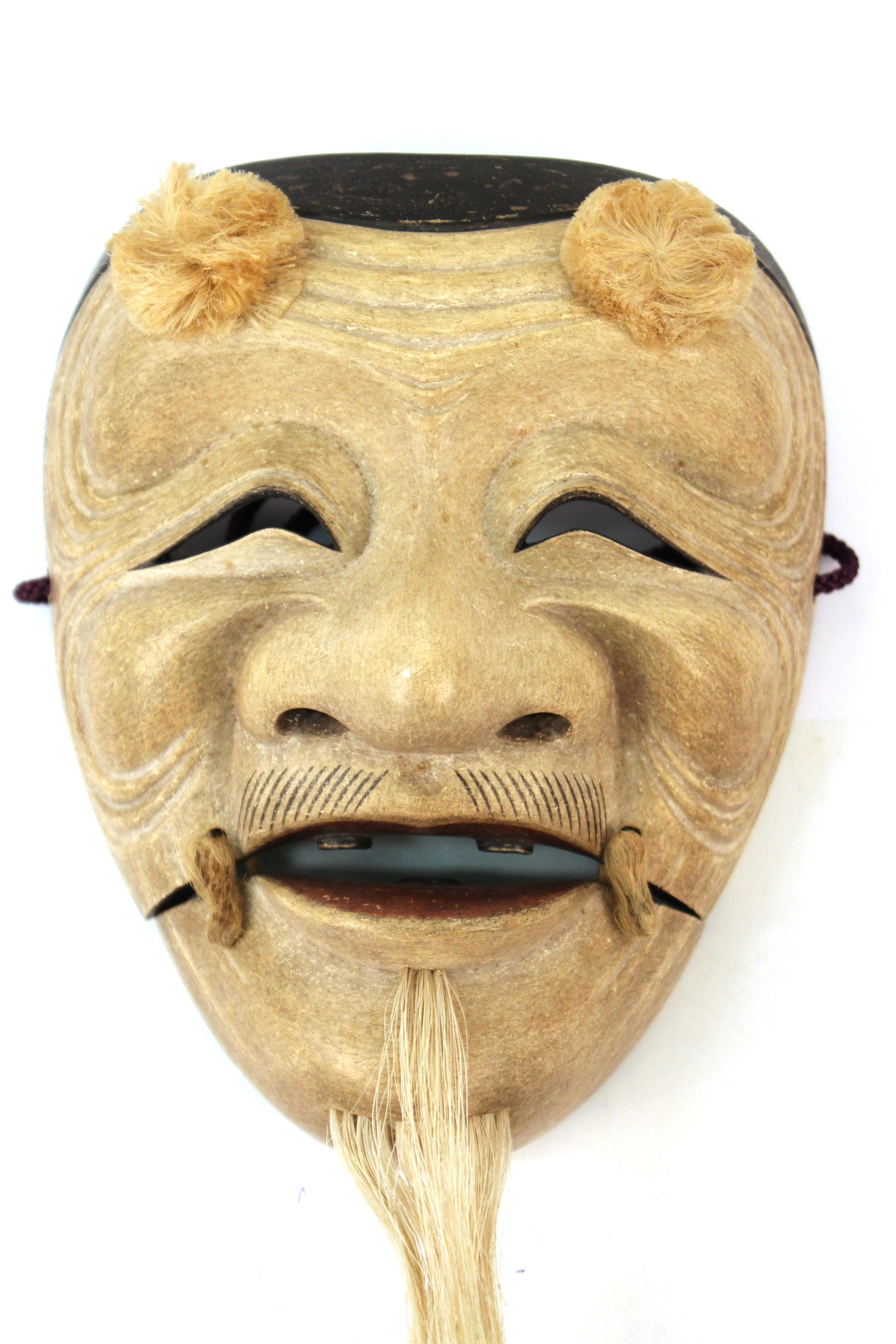 Japanese carved wood Noh mask depicting Okina. The piece was made during the late Edo - early Meiji period in the 19th century. The mask is of an older man with long white beard, which is a sign of wisdom. The Okina mask takes its origin from the
