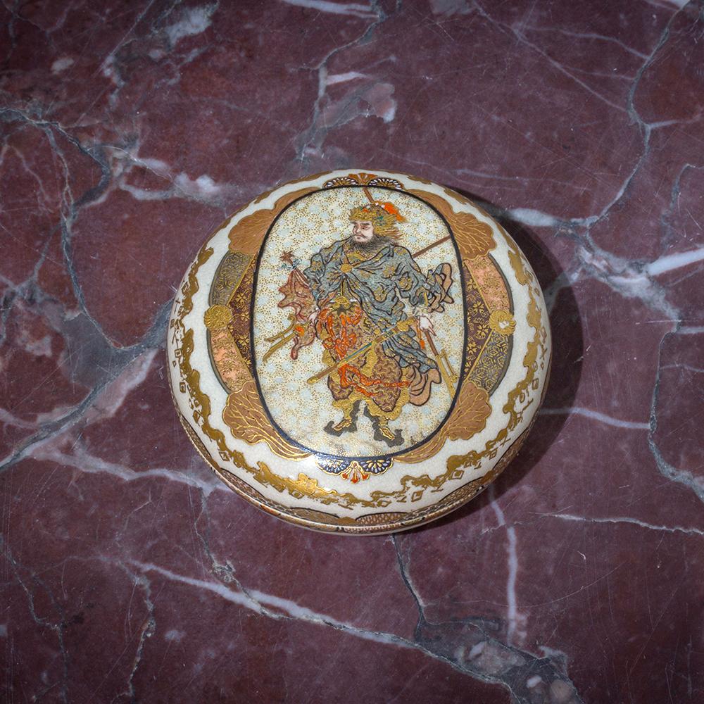DEPICTING BISHAMON ONE OF THE SEVEN LUCKY GODS

From our Japanese Satsuma collection, we are delighted to offer this Japanese Satsuma Kogo by Taizan. The Satsuma Kogo of petit circular form in two halves with a matching lid and base beautifully