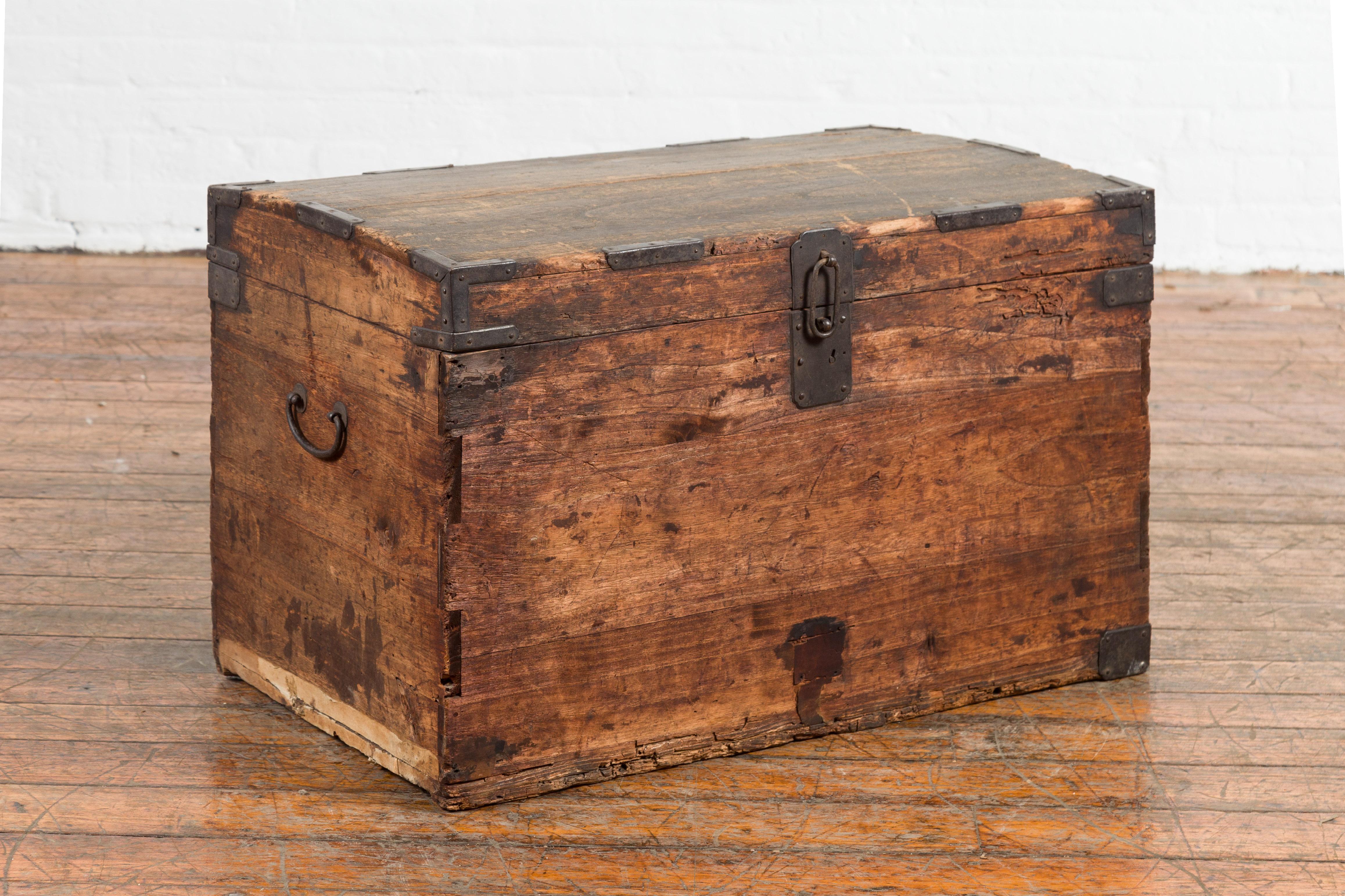 A Japanese Meiji period blanket chest from the 19th century with iron hardware and distressed patina. Created in Japan during the Meiji period, this wooden blanket chest features a slightly domed top accented with iron details, opening to reveal a