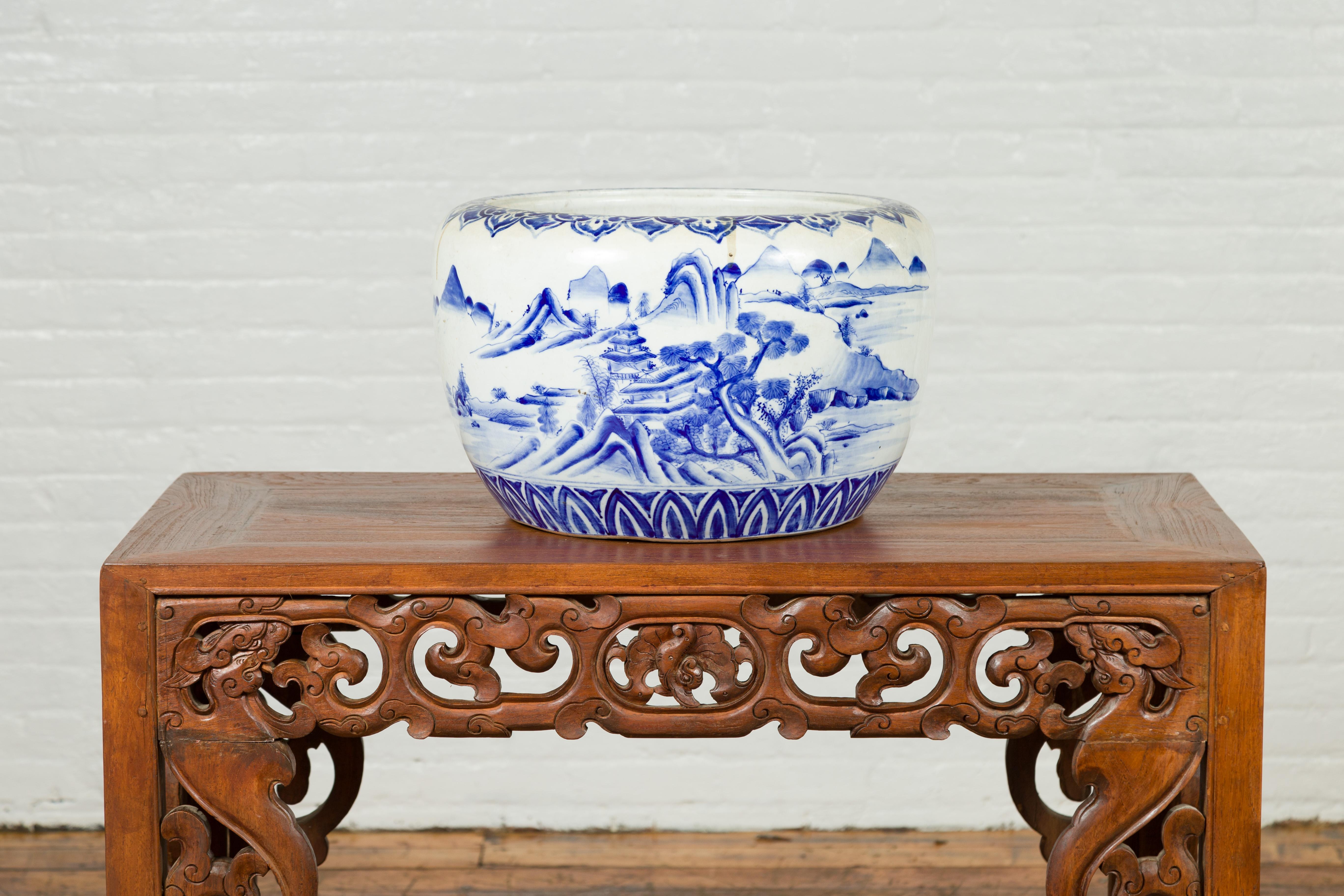 A Japanese Meiji period blue and white porcelain planter from the 19th century, with landscape scenes. Created in Japan during the Meiji period, this circular planter features a blue and white decor depicting exquisite landscape scenes with