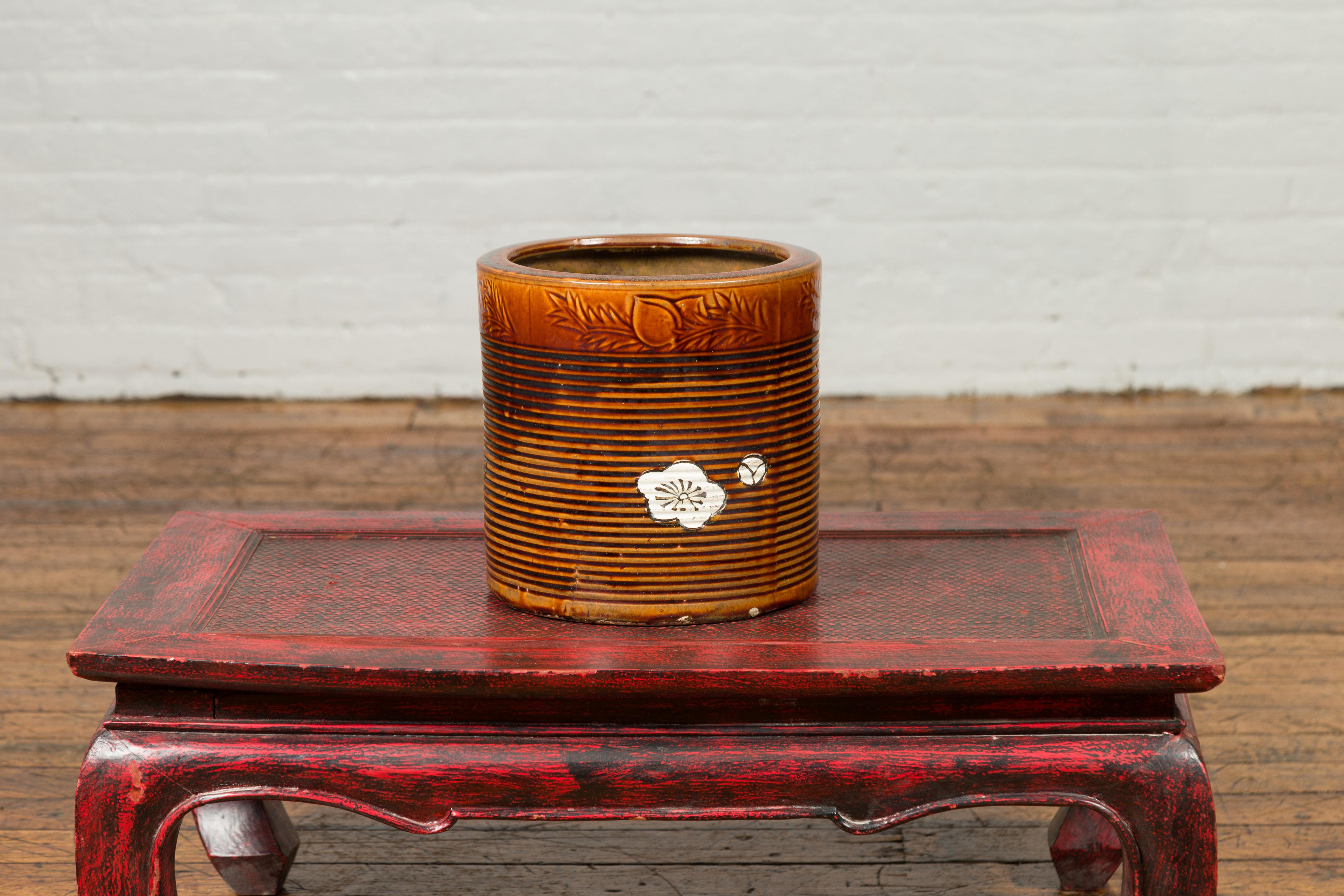 A Japanese Meiji period hibachi planter from the 19th century, with floral motifs and burnt orange patina. Created in Japan during the Meiji period, this hibachi was used for cooking or warming sake or tea. Presenting a cylindrical silhouette