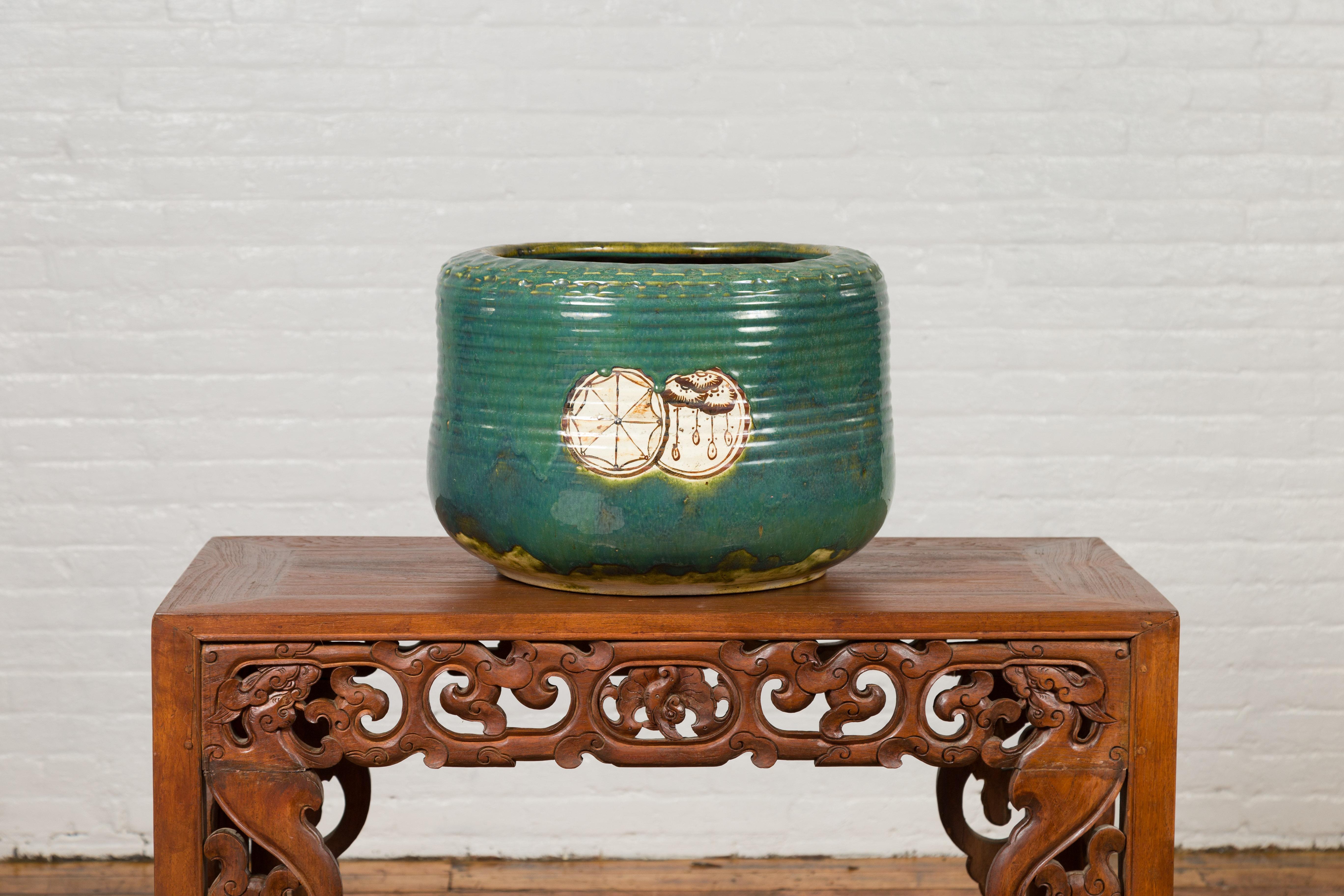An antique Japanese Meiji period round Oribe planter from the 19th century, with decorative motifs. Created in Japan during the Meiji period, this 19th century planter draws our attention with its yellow and green Oribe glaze perfectly contrasted by