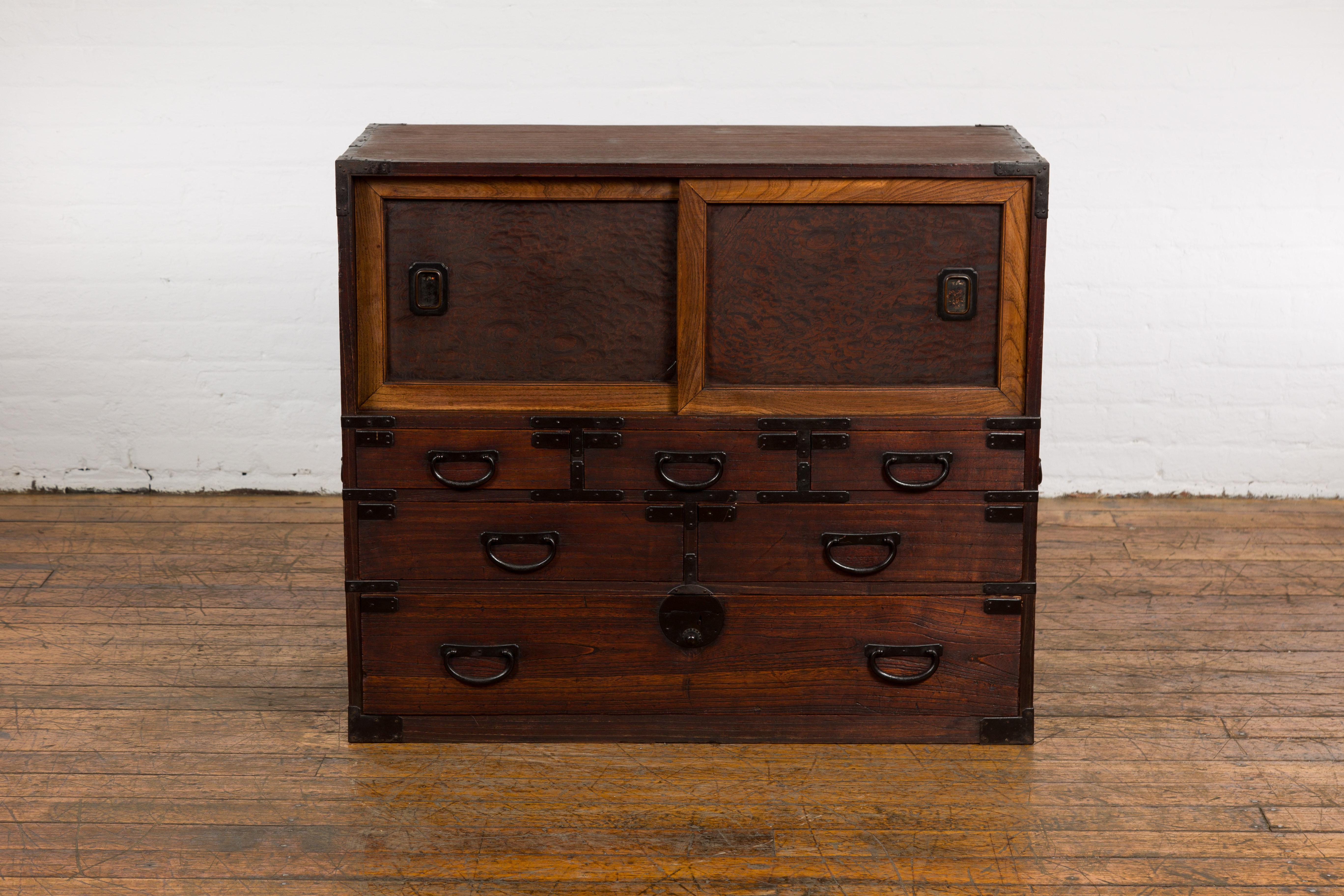 Japanese Meiji period Tansu clothing chest from the 19th century with two sliding doors, six drawers, iron hardware and custom finish. A captivating blend of tradition and artistry, this Japanese Meiji period Tansu clothing chest from the 19th