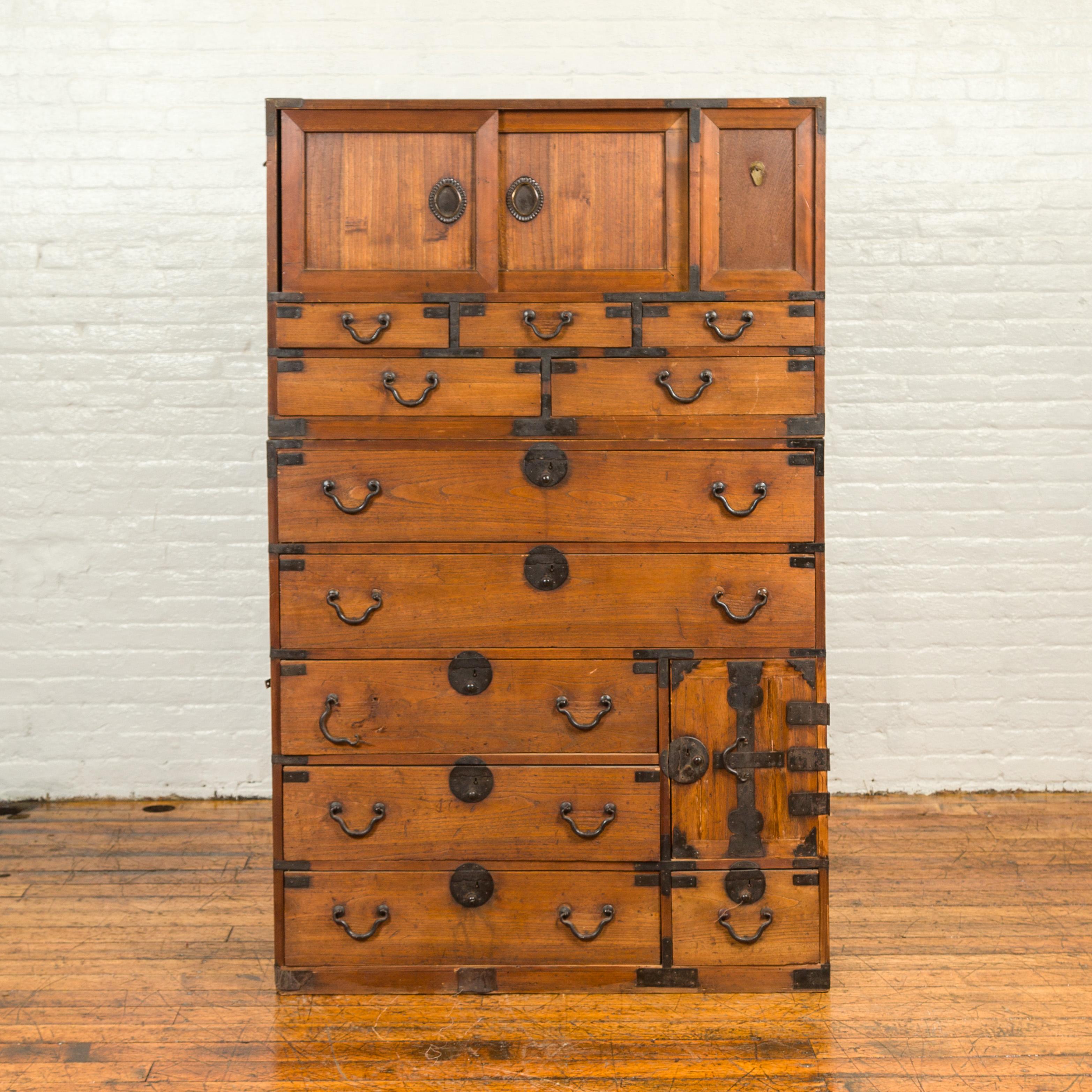 A tall Japanese Meiji period tansu chest from the late 19th century, with drawers and sliding panels. Born in Japan during the second half of the 19th century, this two-section tall tansu chest features two sliding panels and a removable one in its