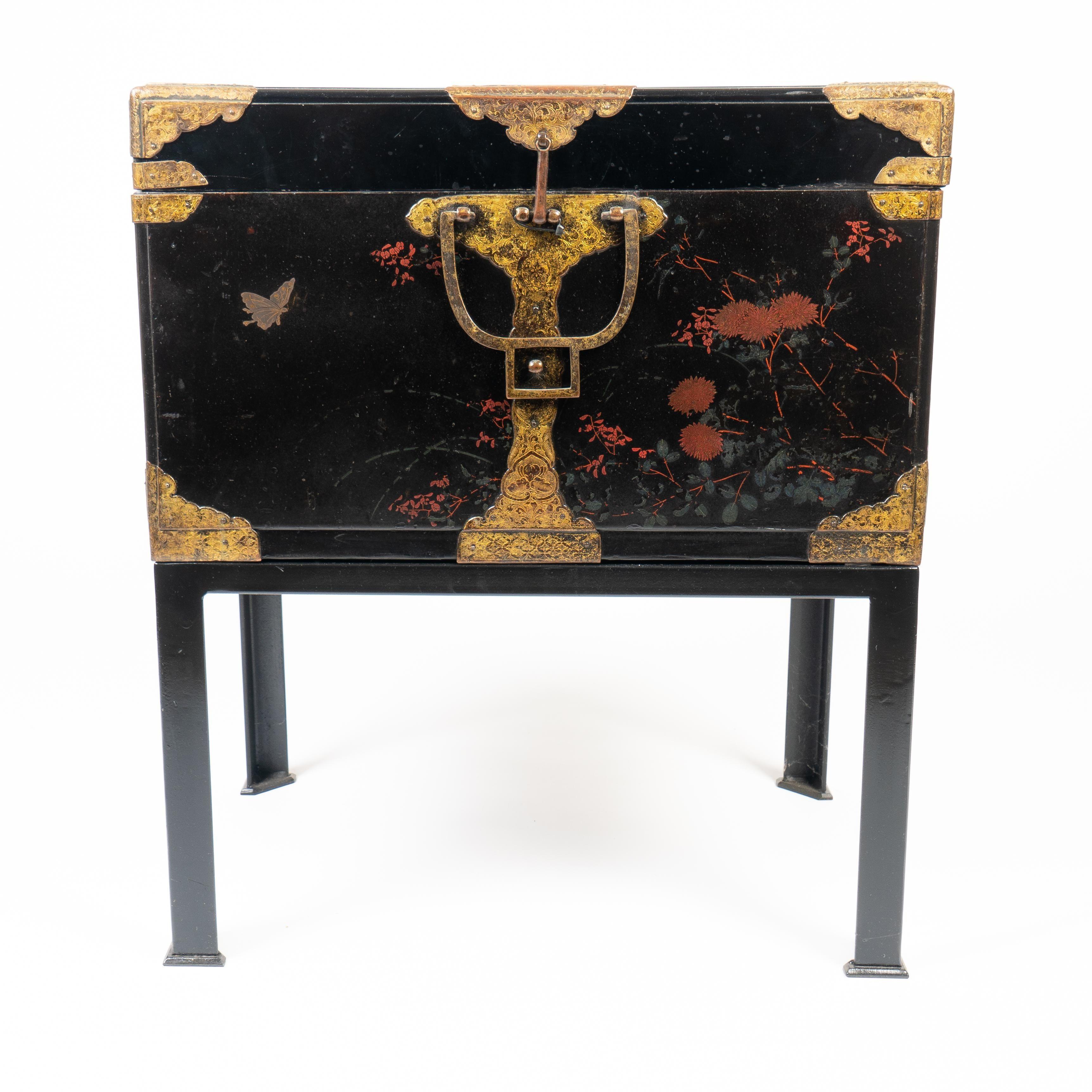 Japanese black lacquered wood trunk with engraved cast brass corner mounts and bails for the lift off cover. The brasses retain traces of their original gilding. All four sides of the case have been decorated in a restrained design of flowers and