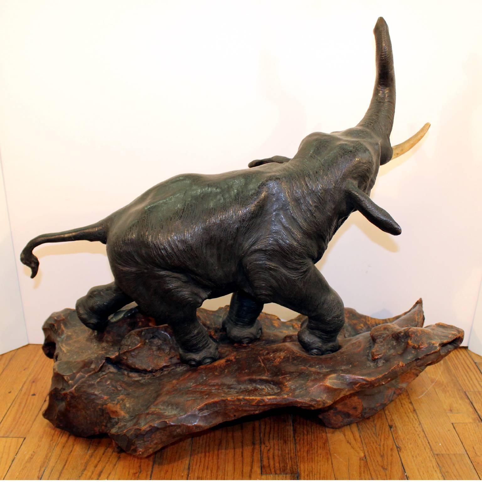 A Japanese Meiji period bronze elephant sculpture on its original burl-wood base. Old repair to the tail; some paint chips to bronze trunk; unsigned.