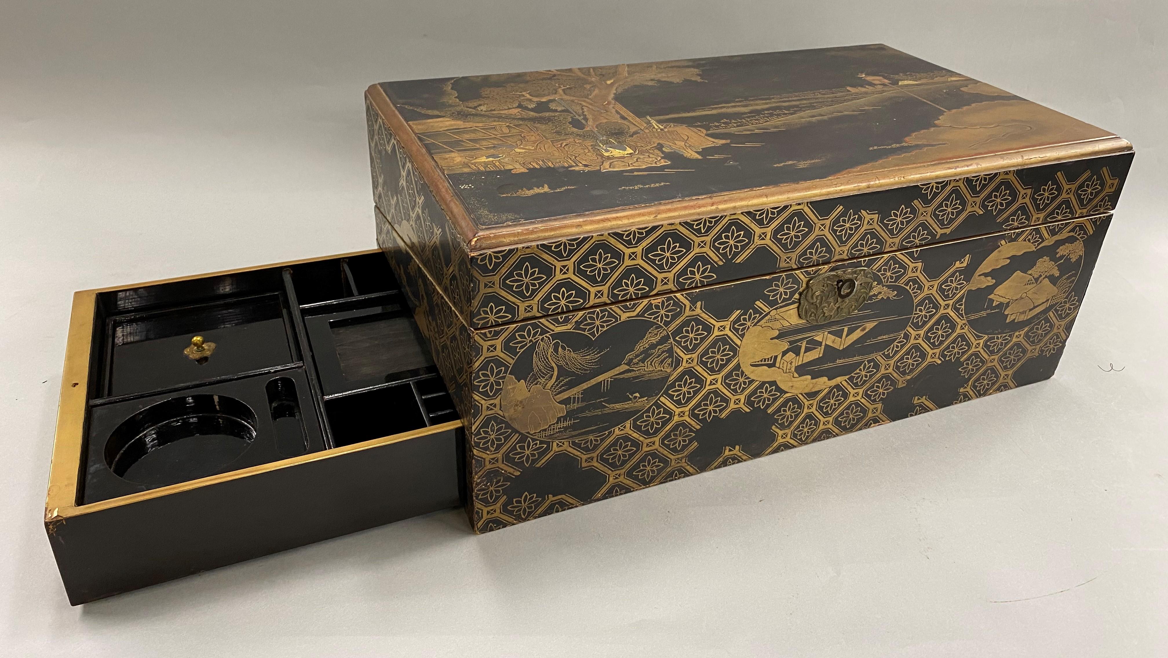 An excellent quality Japanese Meiji period carved wooden writing box or lap desk with compartmentalized interior. With gilt landscape decoration of village scenes accented with geometric patterns around the exterior on all sides, opening to reveal a