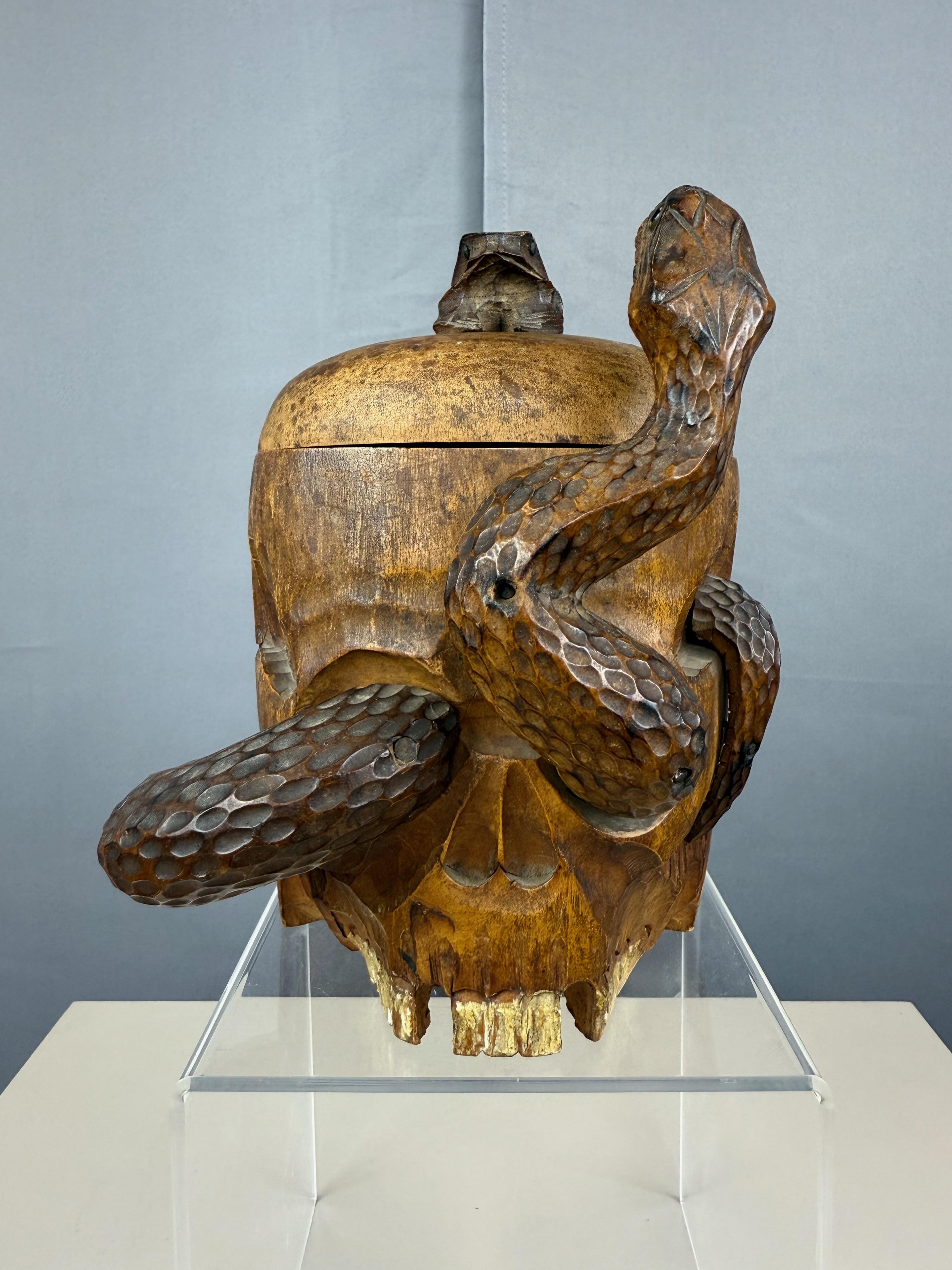 A late 19th century Japanese Meiji period (1868—1912) hand-carved and hand-painted wood skull, snake, and frog motif tobacco humidor. 

A transfixing memento mori piece originally made to hold loose tobacco, with fantastic craftsmanship and artistic
