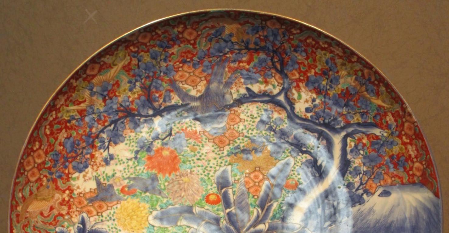 Unique Japanese late-19th century very large Imari Meiji period (circa 1880) signed porcelain charger in iron-red, cobalt blue and green. It showcases a dramatic landscape. The bottom half is boldly hand-painted in cobalt blue underglaze, while the