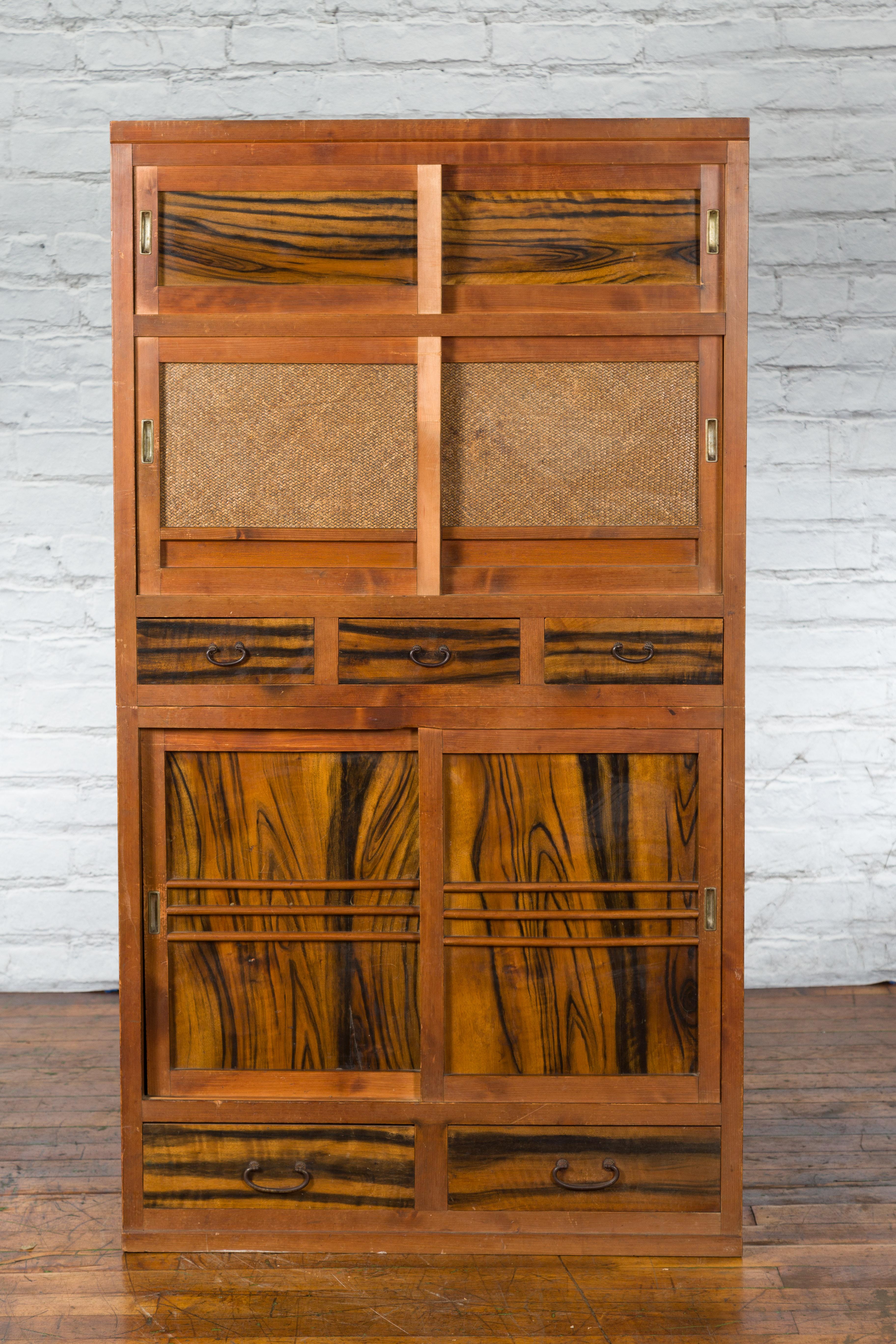 A Japanese Meiji period wooden cabinet from the 19th century, with sliding doors, five drawers and rattan inserts. Created in Japan during the second half of the 19th century, this Meiji cabinet features a linear silhouette perfectly complimented by