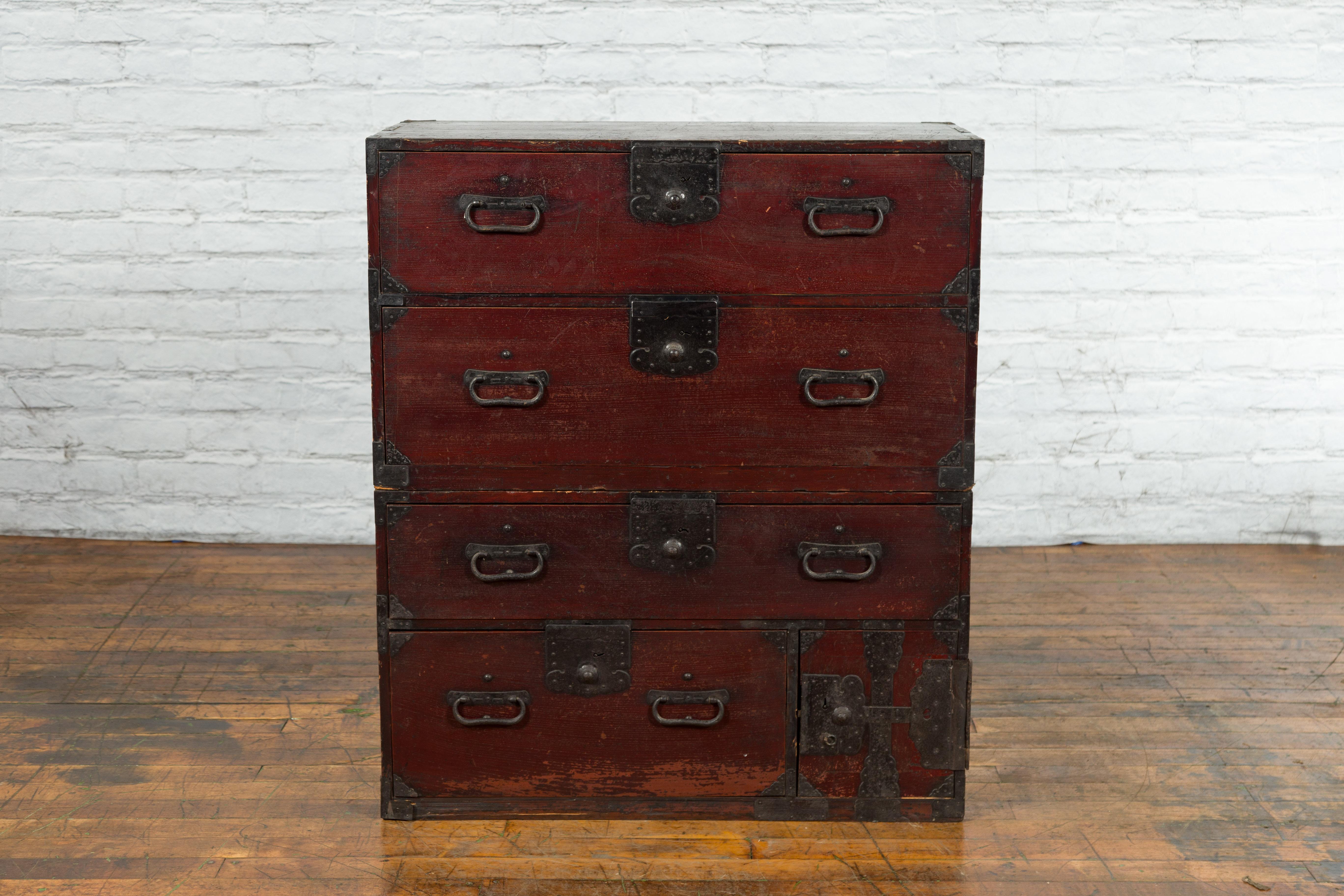 An antique Japanese Meiji period two-part tansu chest from the late 19th century with dark red lacquer, iron hardware, small safe and carrying handles. Created in Japan during the Meiji period (1868-1912), this wooden chest called an Isho-Dansu