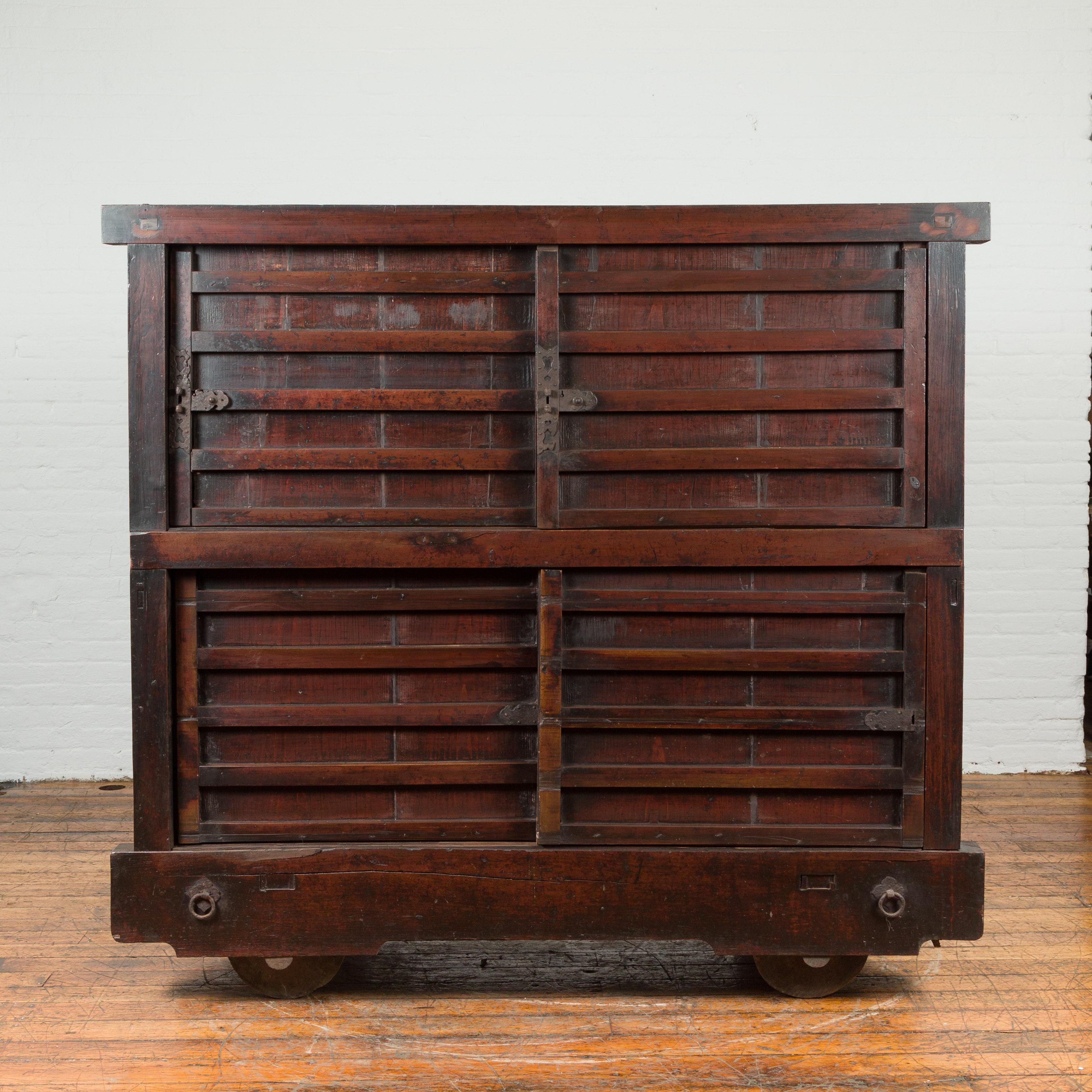 A Japanese Meiji period merchant's chest from the late 19th century, with wheels, sliding doors and dark patina. Created in Japan during the second half of the 19th century, this merchant's chest features a dark brown patina perfectly complimenting