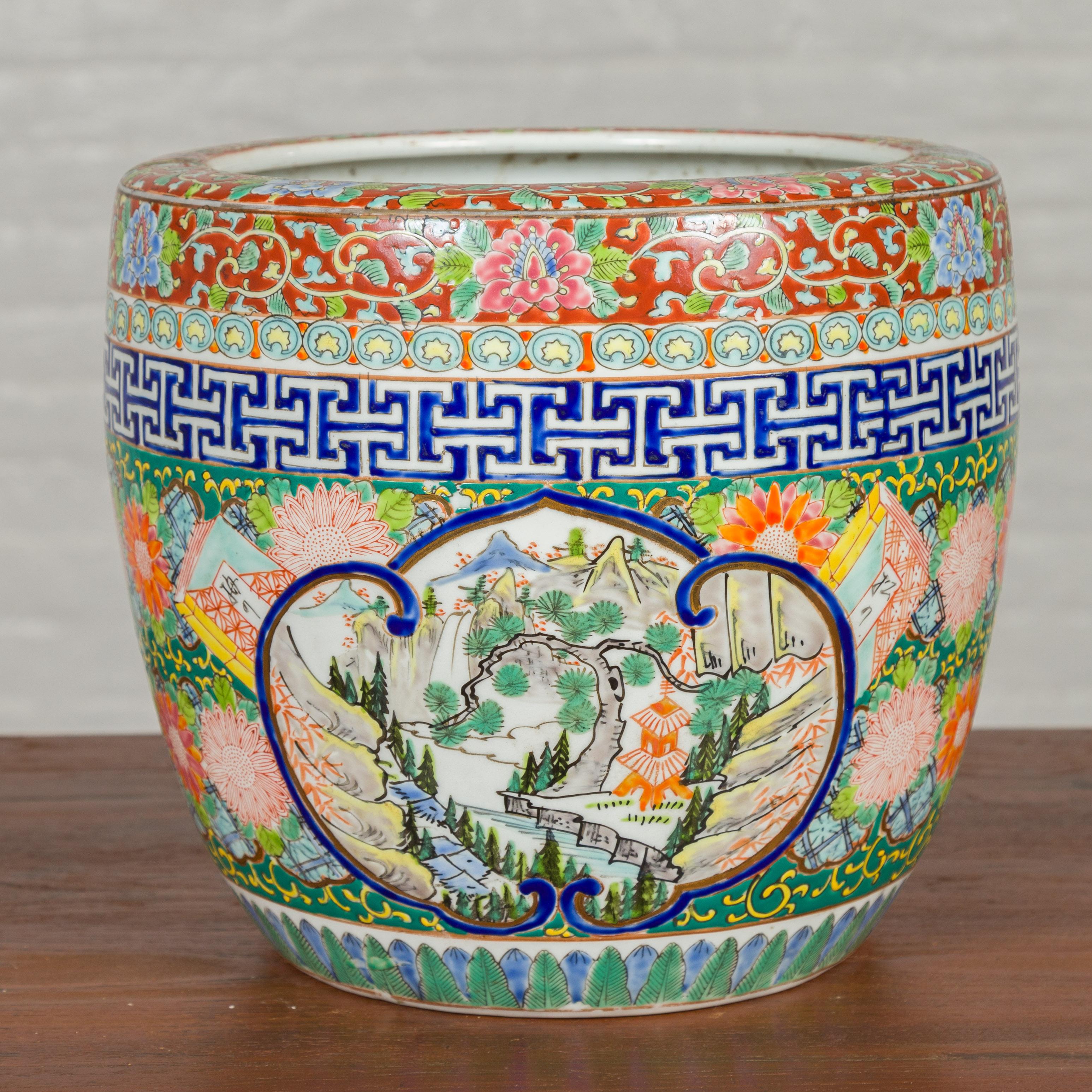 A Japanese Meiji period multi-color planter from the late 19th century, with landscape scenes and floral motifs. Crafted in Japan during the Meiji period, this multi-color planter features a scrolling cartouche on two sides, surrounding a