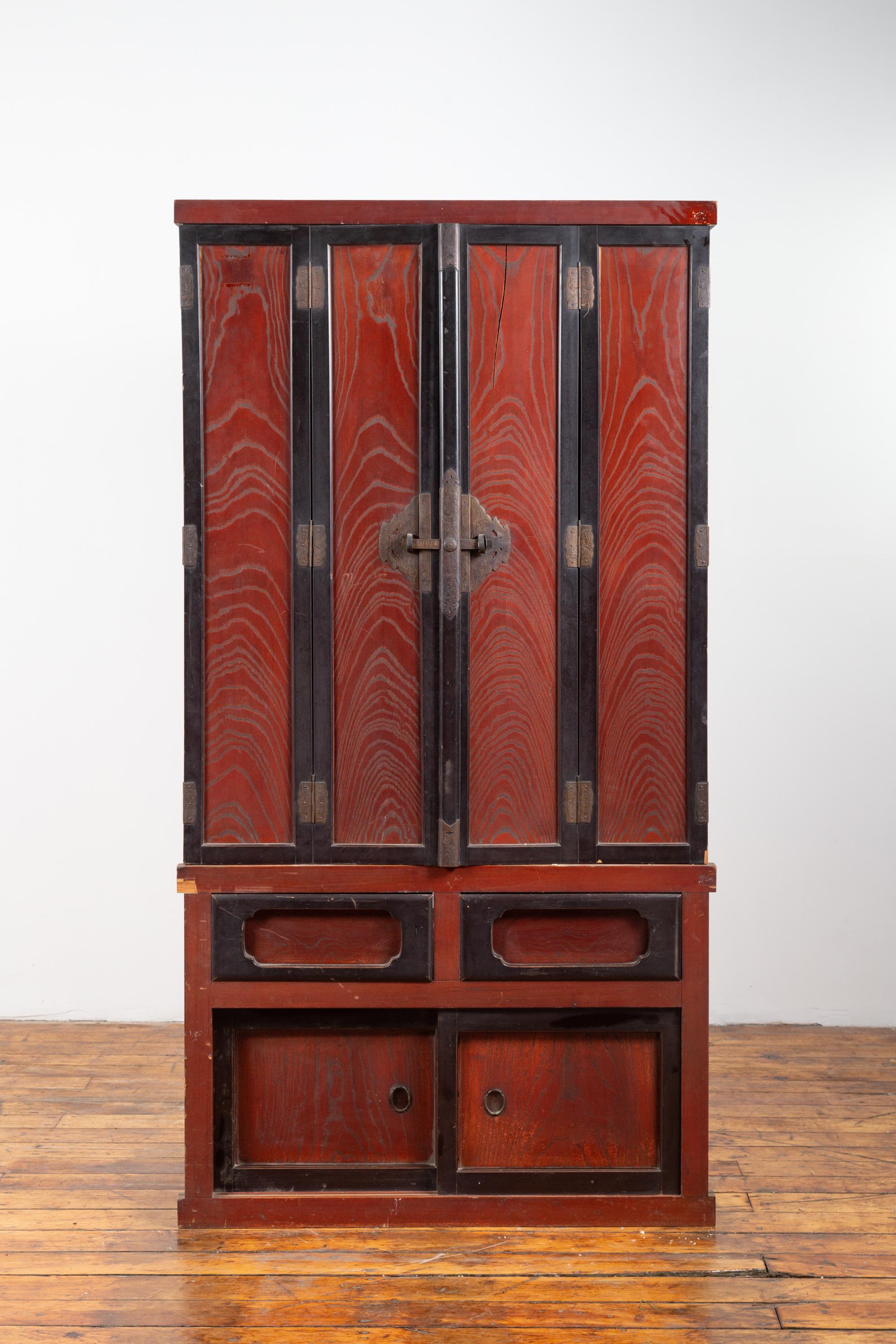 A Japanese Meiji period altar shrine cabinet from the late 19th century, with red and black patina. Born in Japan during the later years of the 19th century, this exquisite wooden cabinet is made of two parts. The upper section presents two folding