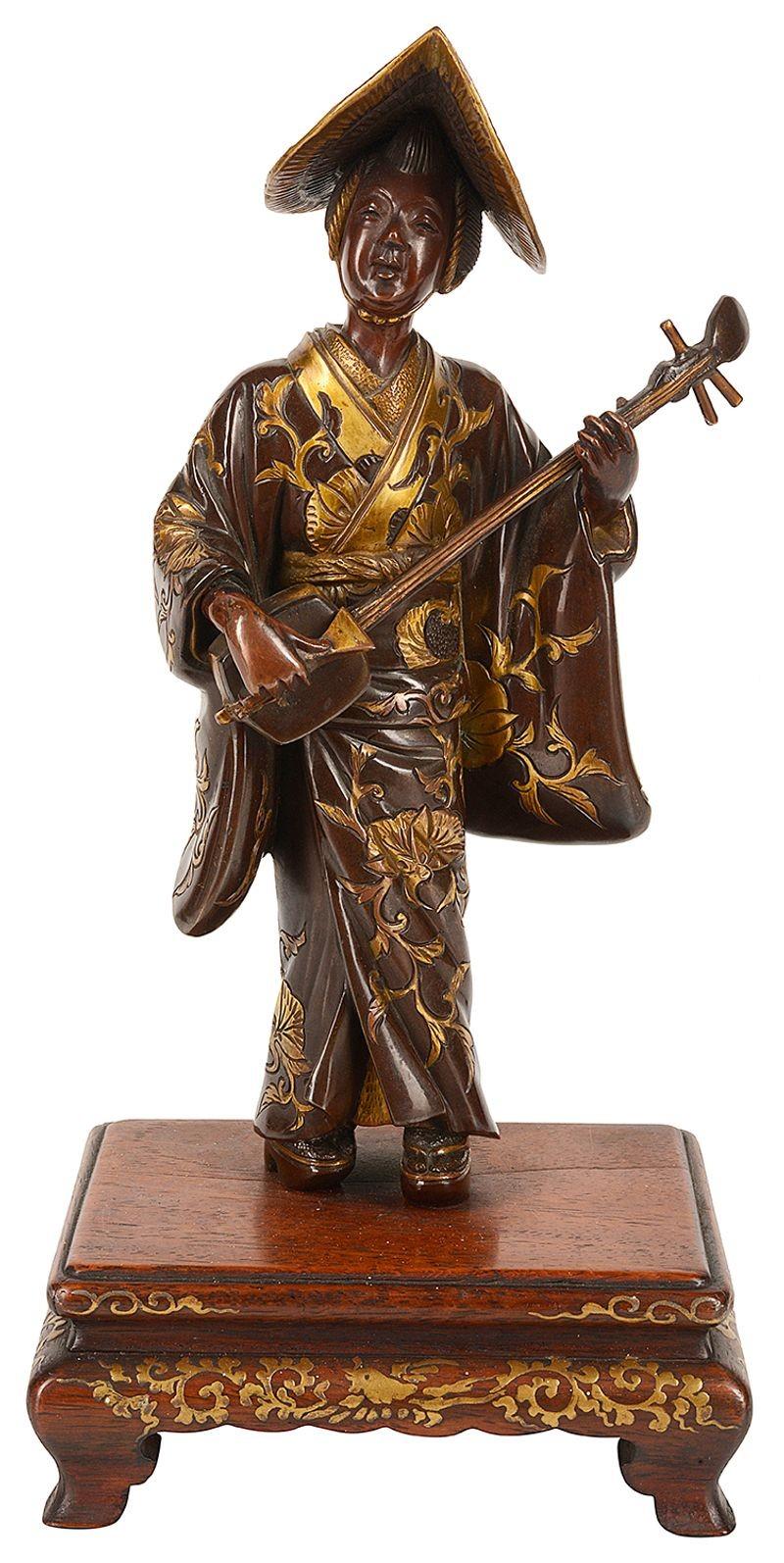A fine quality Meiji period (1868-1912) Miyao bronze statue of a female muscian, having wonderful gilded high lights and mounted on a hardwood stand. Signed at the back on a plaque on her cloak.