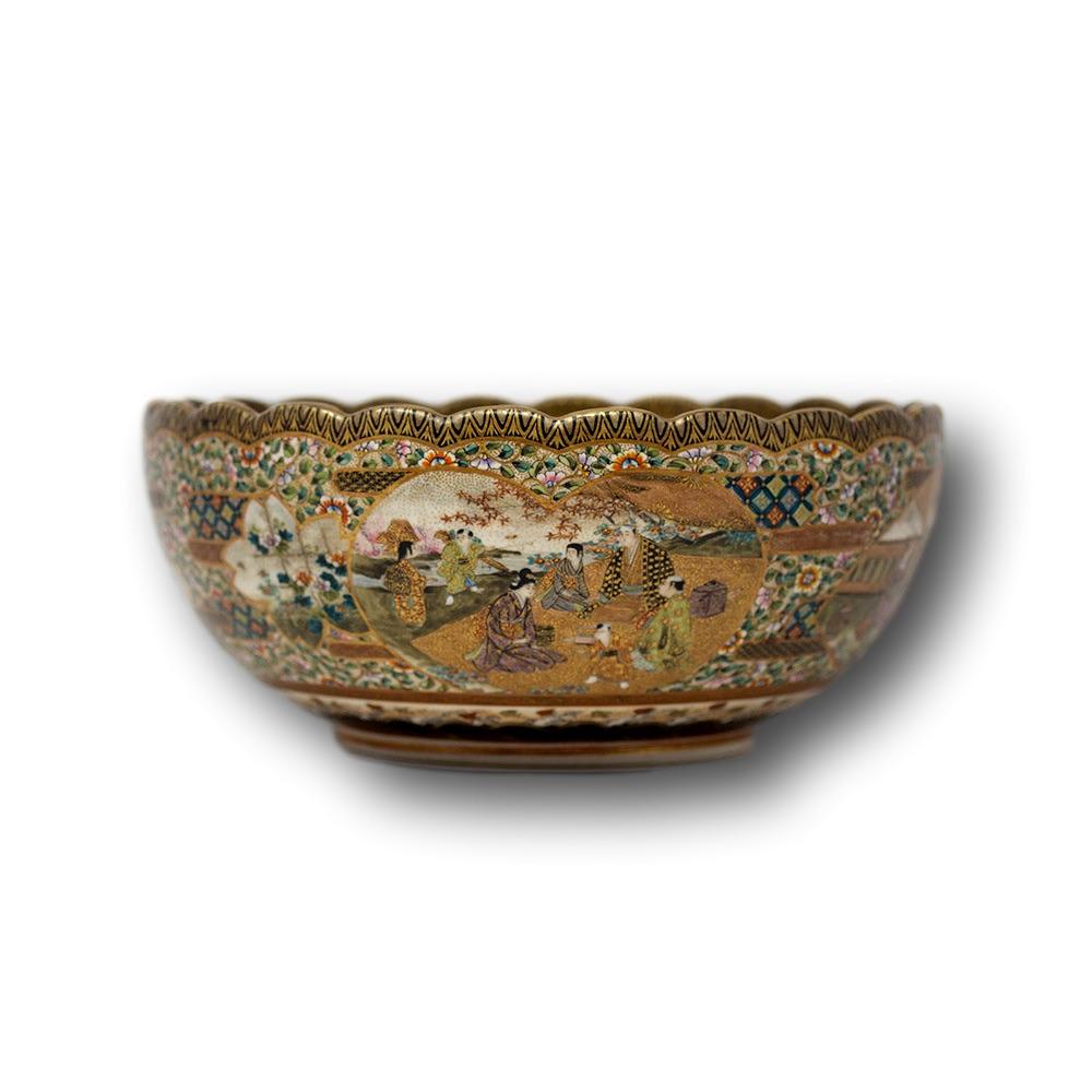 Fine and large Japanese Meiji period satsuma earthenware bowl. The bowl of nice size potted with a scalloped edge, with a black and gold border extensively decorated with scrolling vines and blossoming flowers throughout. The exterior with four