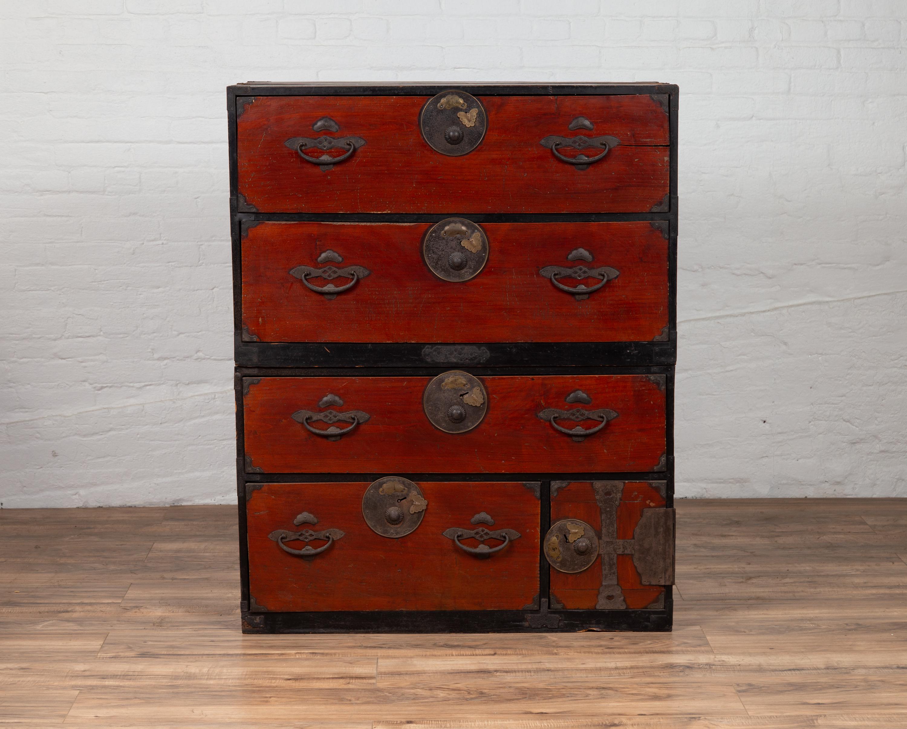 A Japanese Meiji period two-part tansu clothing chest from the 19th century, with round medallion hardware and butterfly accents. Born in Japan during the 19th century, this wooden tansu chest is a fine example of Japan's traditional mobile